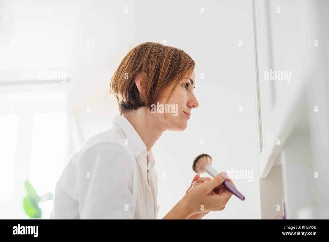 Une routine du matin de jeune femme mise sur un make-up dans une salle de bains. Banque D'Images