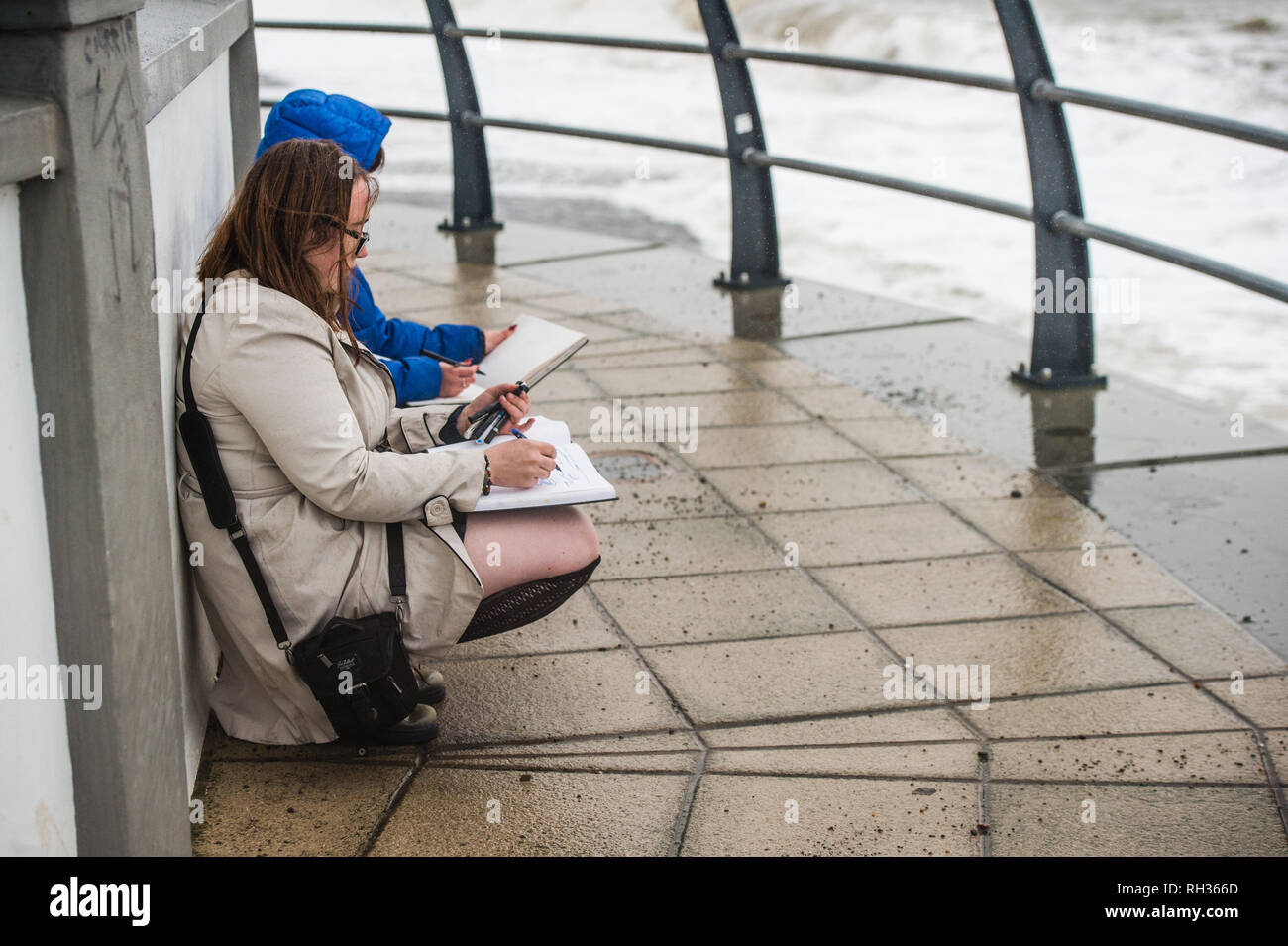 Deux jeunes étudiantes à Aberystwyth University School of Art oudoors et esquisses les vagues causées par l'Orage Diana de Galles UK Banque D'Images