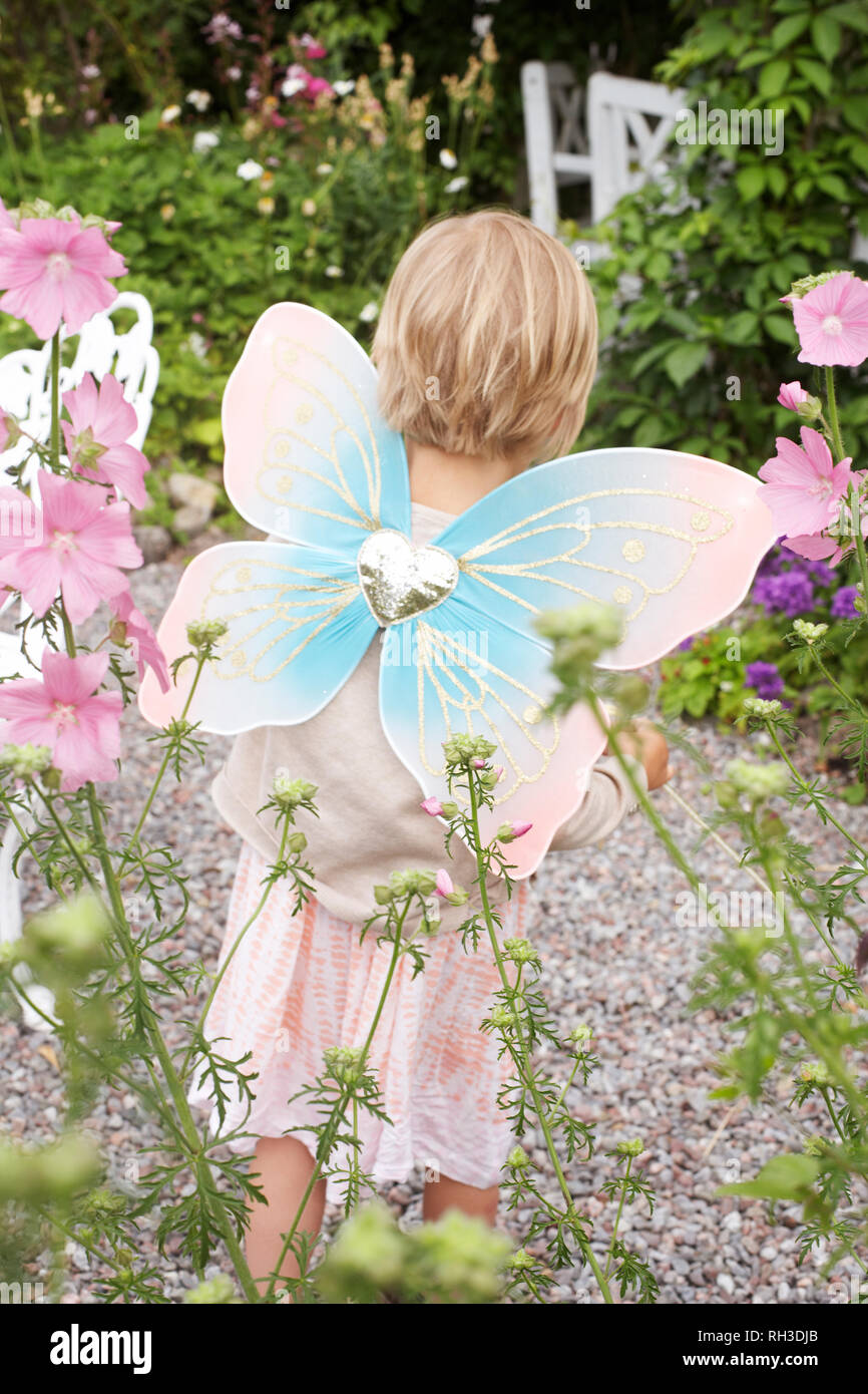 Girl wearing fairy wings in garden Banque D'Images