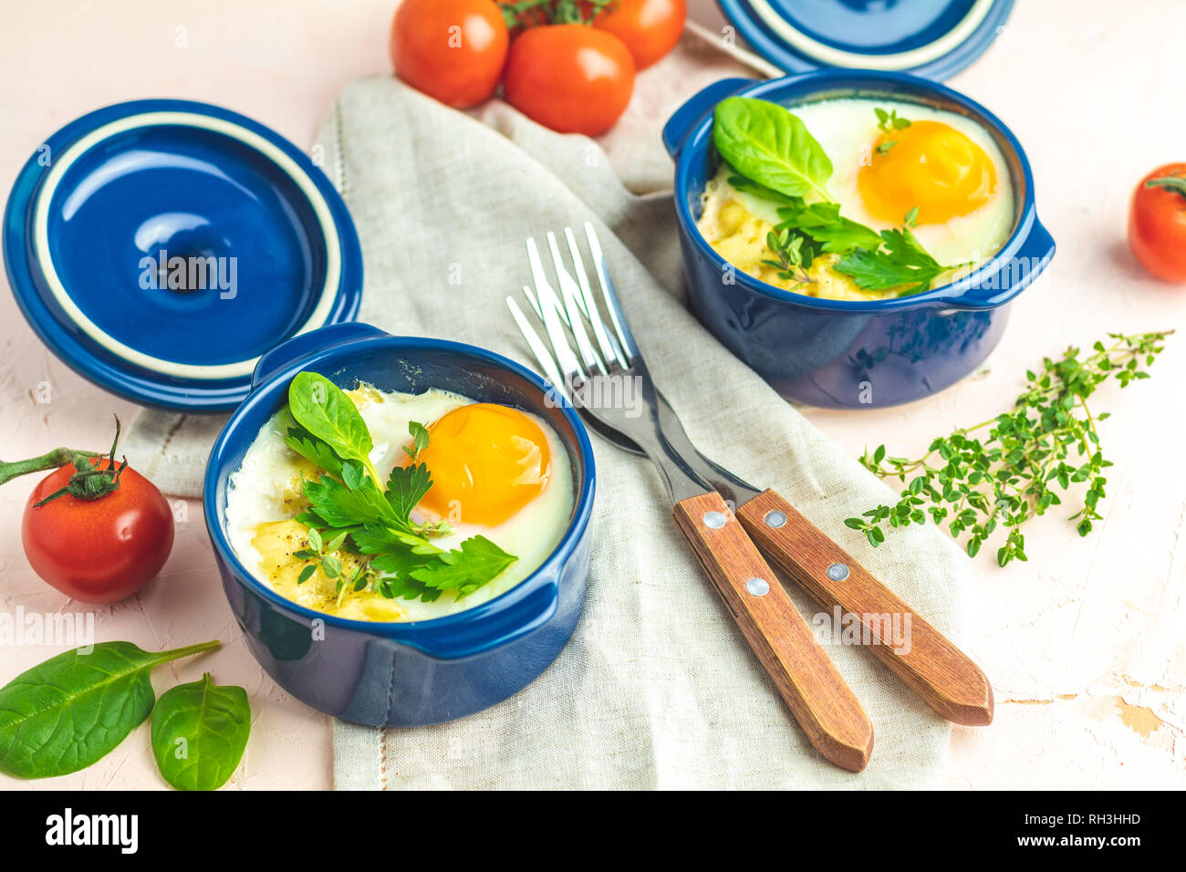 Oeufs cocotte kokot petit-déjeuner français. Oeufs cuits en bleu moules de cuisson en céramique. Cocotte de légumes et portionné oeufs dans le style italien. Banque D'Images