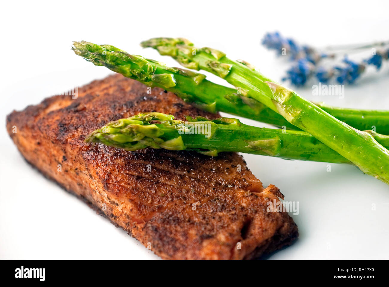 Saumon poêlé servi avec des produits frais, d'asperges cuites à la vapeur et rehaussés d'un brin de lavande. Le saumon est riche en protéines et acides gras oméga-3. Banque D'Images