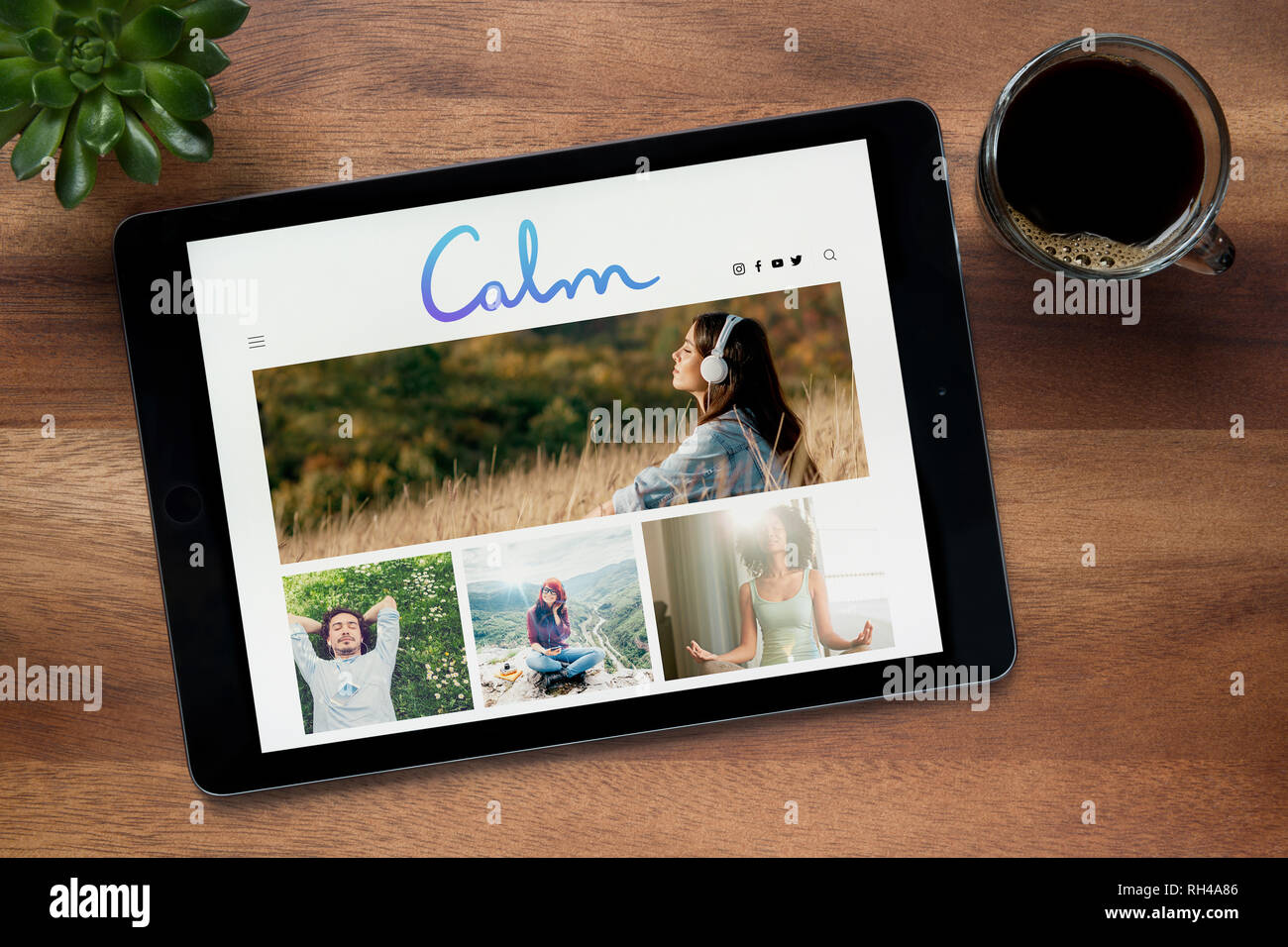 Le site web de calme est vu sur un iPad tablet, sur une table en bois avec une machine à expresso et d'une plante (usage éditorial uniquement). Banque D'Images