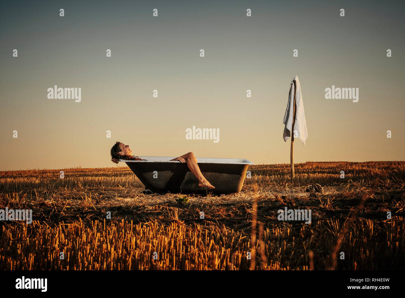 Woman relaxing in bathtub in rural field Banque D'Images