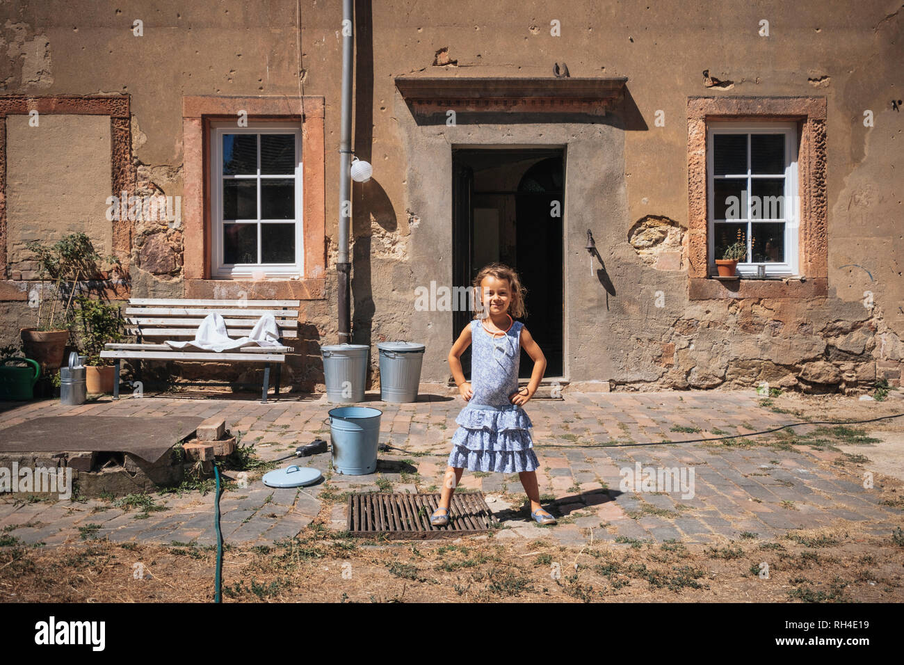 Portrait confiant Girl standing in front of sunny farmhouse Banque D'Images