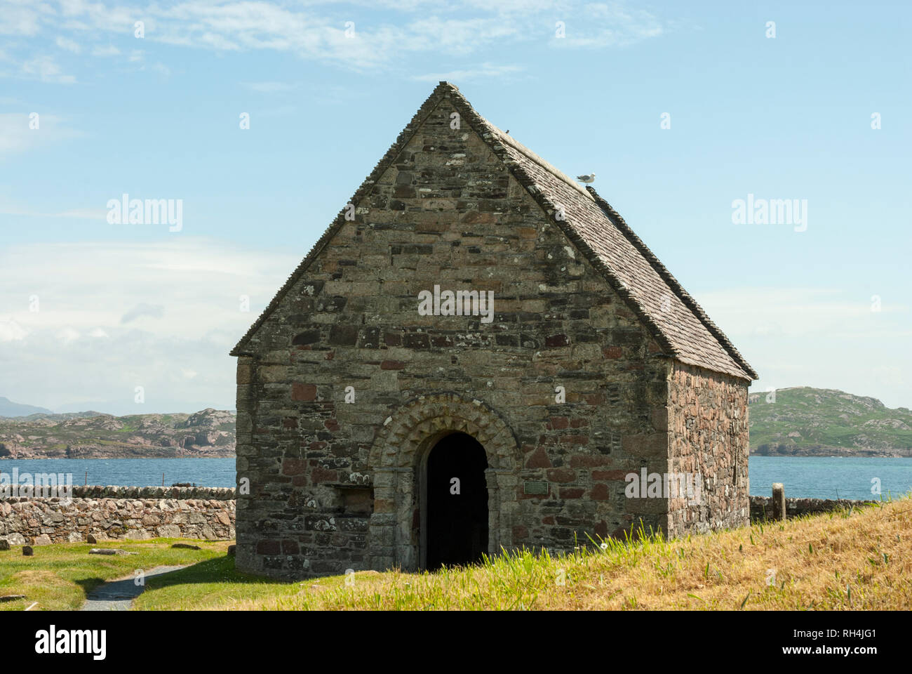L'ancien 12ème siècle Chapelle St Rore avec le son d'Iona dans l'arrière-plan sous le soleil d'été. Banque D'Images