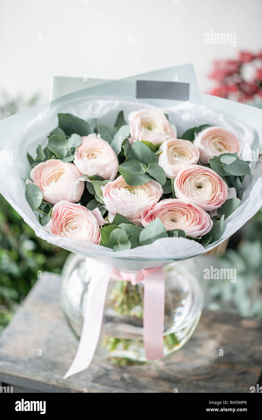 Renoncule de Perse en vases de verre. Bouquet de renoncules rose pâle avec  des fleurs d'eucalyptus vert. Beau bouquet fraîchement coupées dans un vase  sur la table en bois Photo Stock -