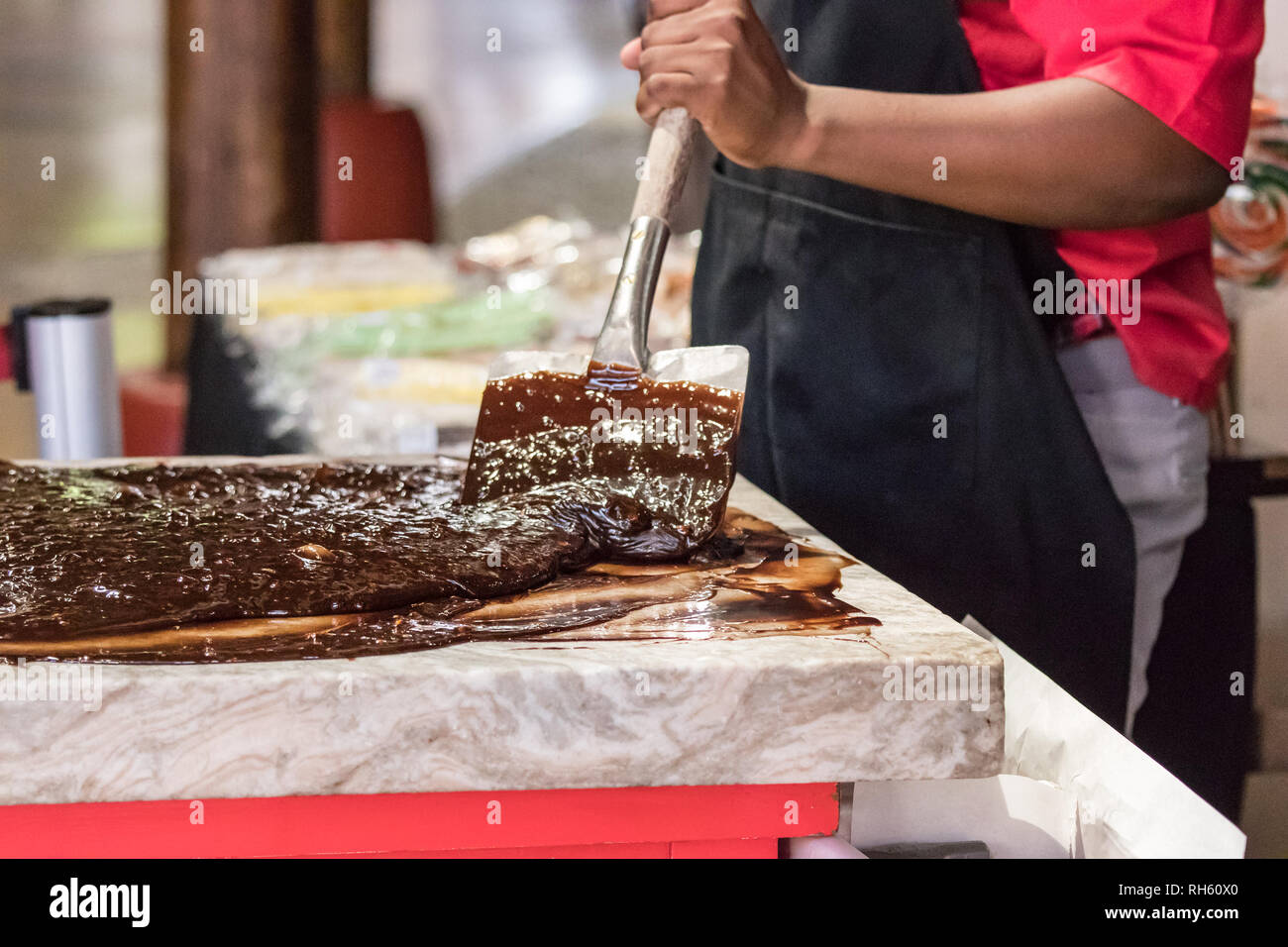Libre d'un artisan travailleur chocolat chocolat fusion mélange avec des spatules sur une table en marbre. Banque D'Images