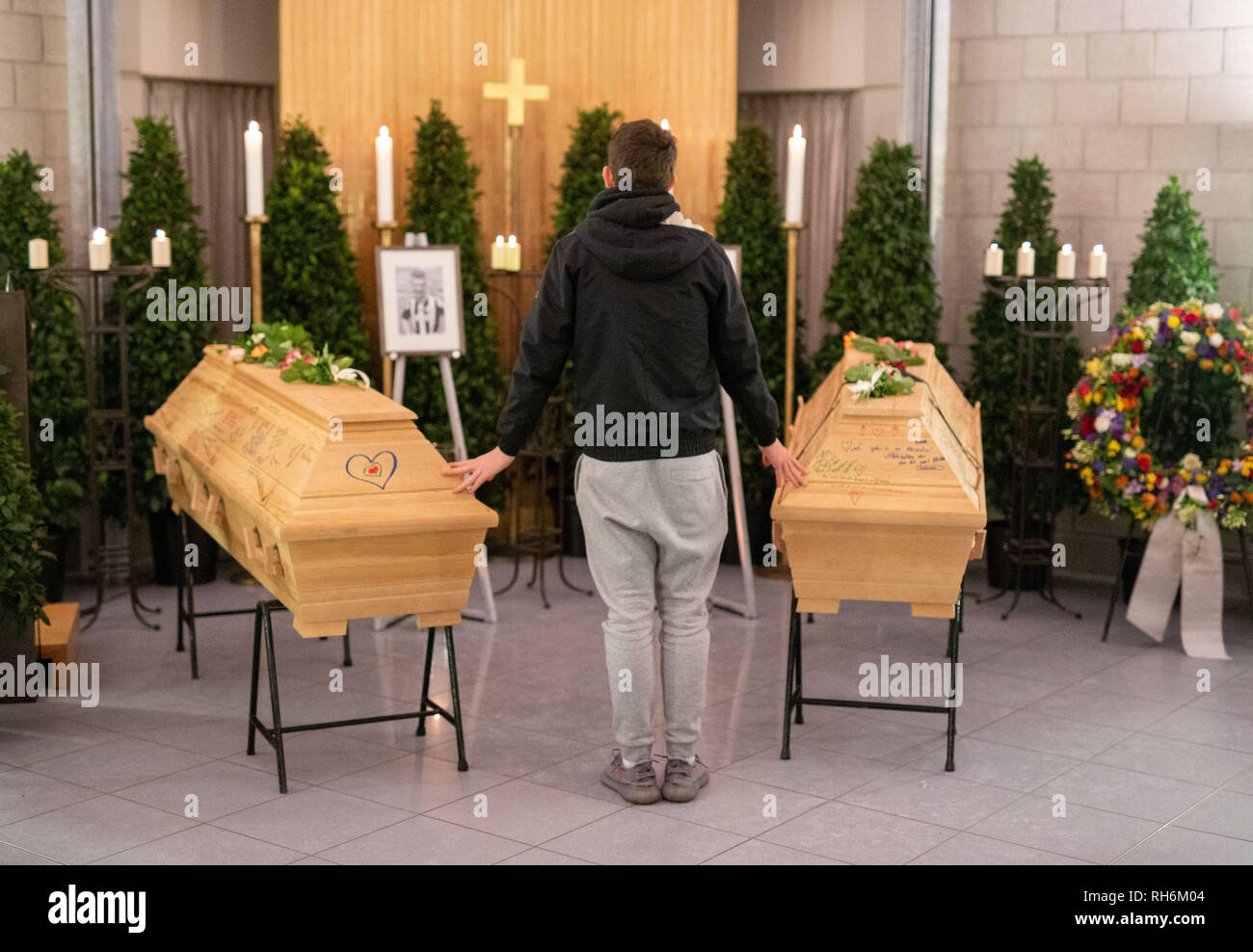 Heroldsberg, Allemagne. 06Th Feb 2019. Un jeune homme pose ses mains sur les deux cercueils à un service funèbre. Une semaine après une querelle fatale dans une gare S-Bahn de Nuremberg, parents, collègues et amis au revoir aux deux jeunes tués à Heroldsberg en franc. Credit : Lino Mirgeler/dpa/Alamy Live News Banque D'Images