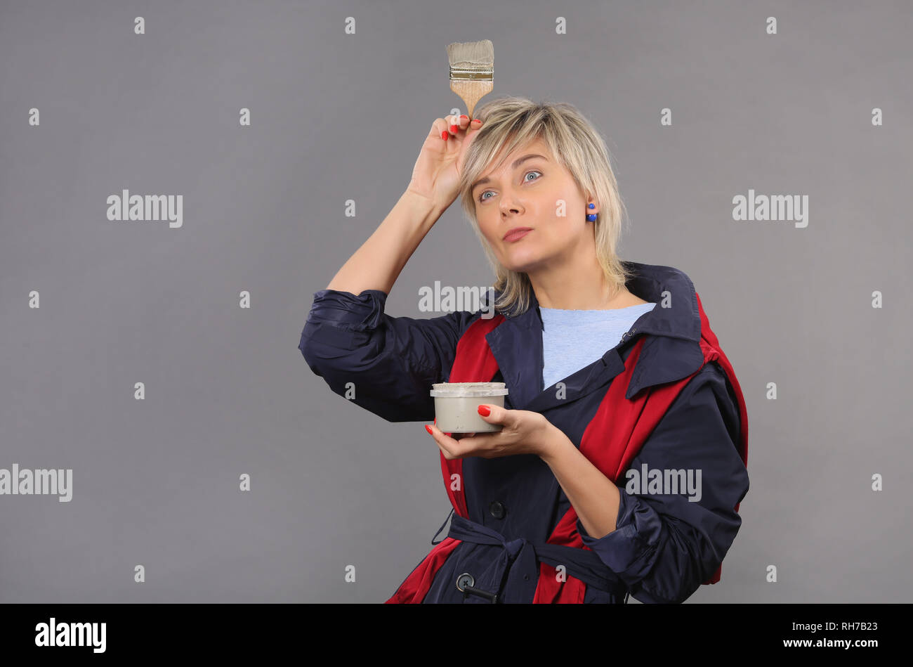 Femme peintre, un artiste, dans un pull et la robe, tenant un pinceau et peinture gris, il pense à la peinture, 40e, sur fond isolé Banque D'Images