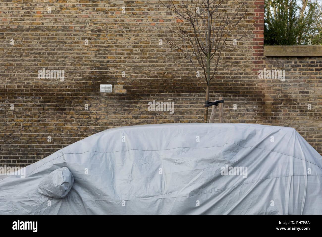 Une voiture classique est couvert sous des bâches en plastique lorsqu'il est parqué dans une petite rue dans le sud de Londres, le 29 janvier 2019, dans la région de Herne Hill, Lambeth, Londres, Angleterre. Banque D'Images
