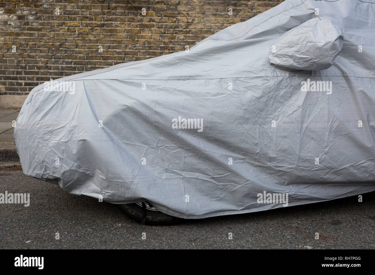 Une voiture classique est couvert sous des bâches en plastique lorsqu'il est parqué dans une petite rue dans le sud de Londres, le 29 janvier 2019, dans la région de Herne Hill, Lambeth, Londres, Angleterre. Banque D'Images