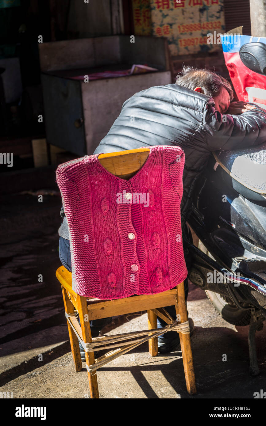 L'homme de dormir sur une chaise au marché 1285 Shangri-la, vieille ville de Lijiang, Yunnan Province, China Banque D'Images