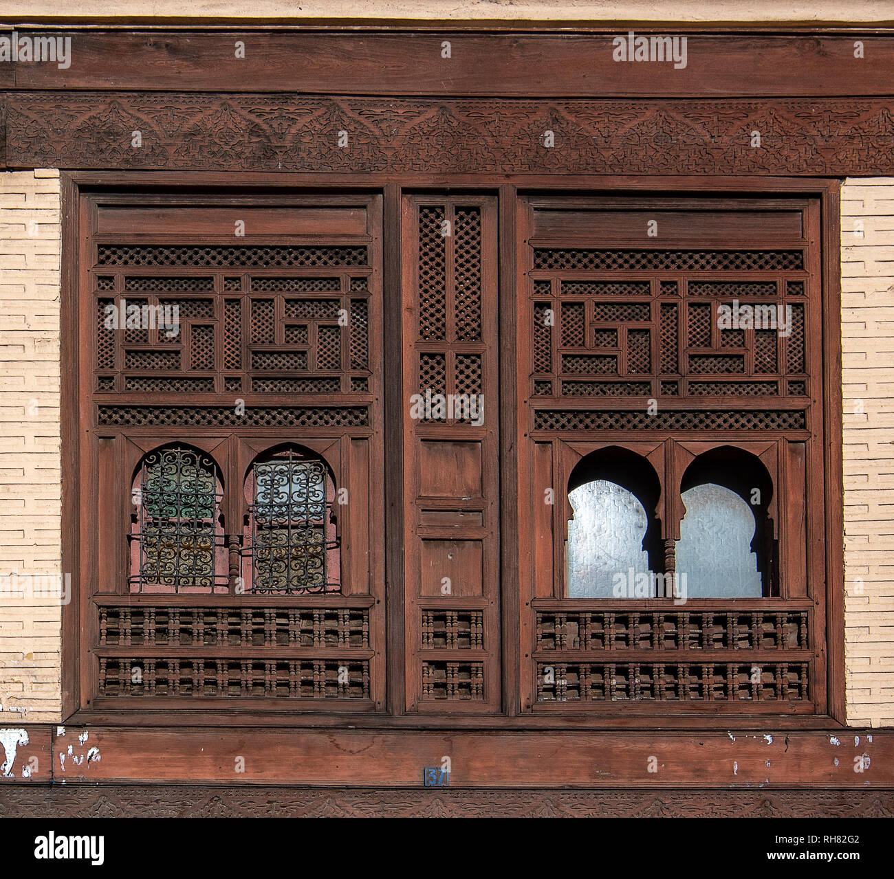 Fenêtres en bois et de carrelage mural et de sol de mosaïque. Arabesque colorée ornée et traditionnelles sculptures murales au-dessus d'un riad marocain en . Banque D'Images