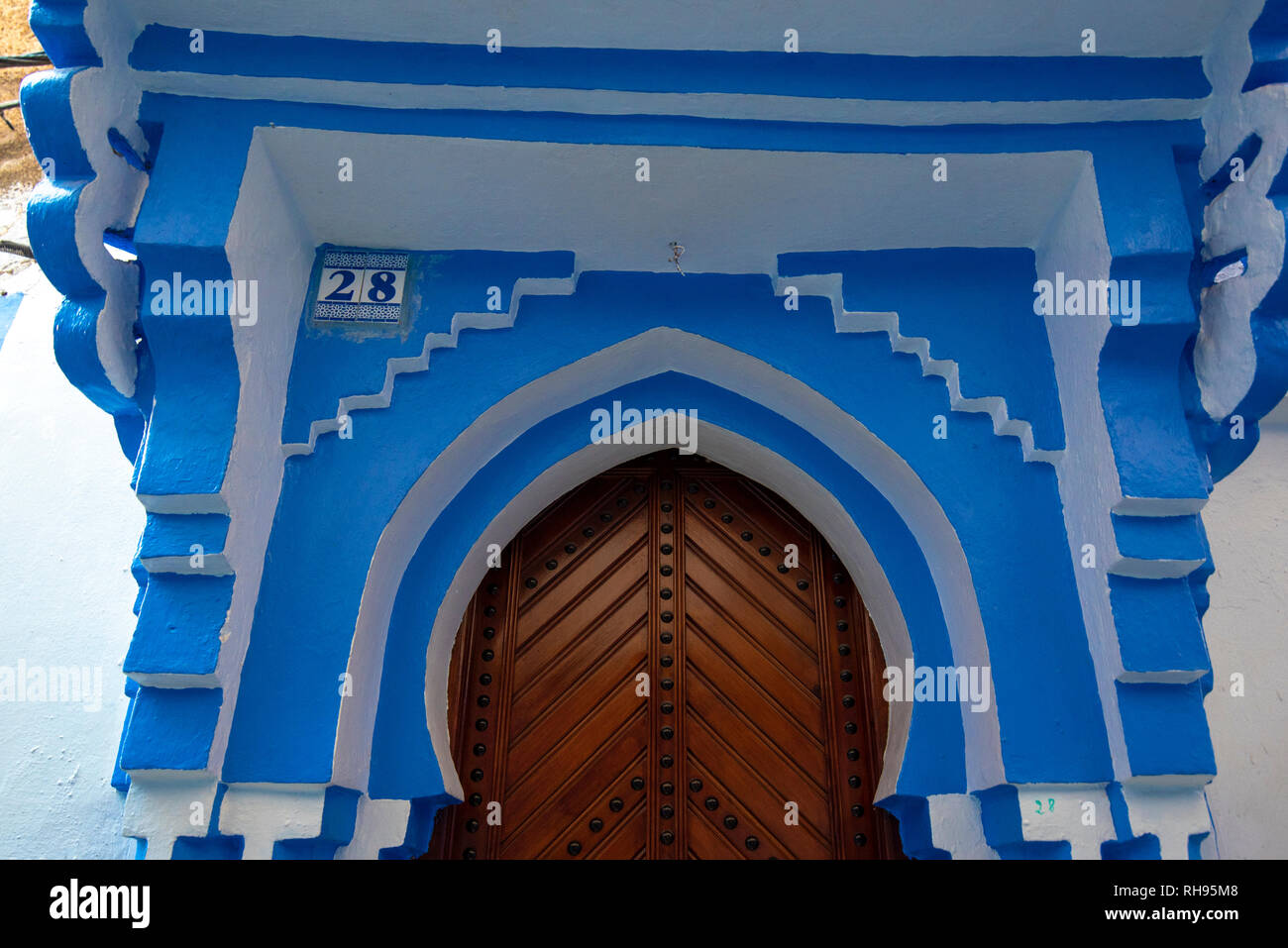 Typique, vieux, brown, finement sculptés, porte cloutée riad marocain et porte cadre et maison ancienne. bleu ville dans la médina de Chefchaouen, Maroc Banque D'Images