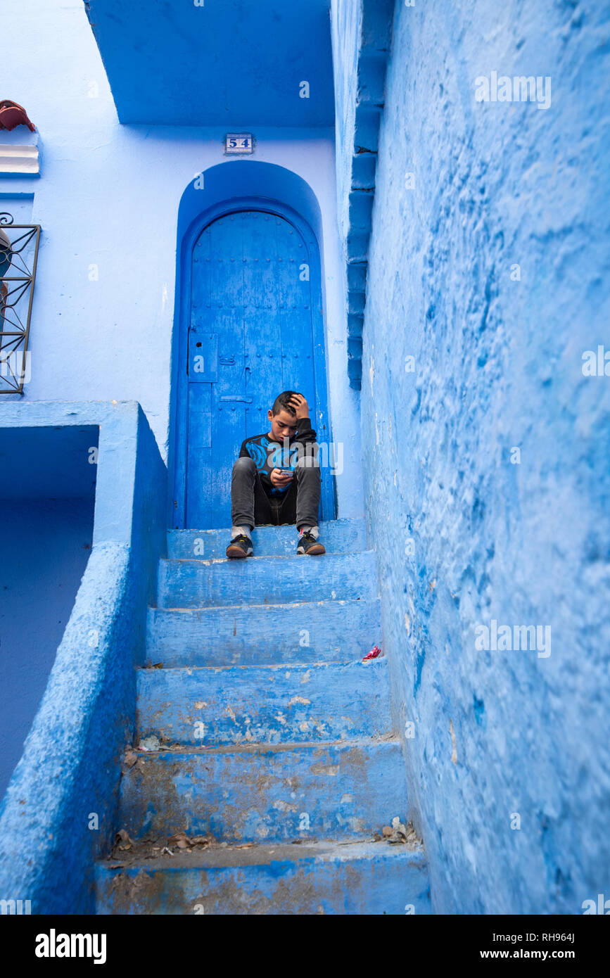 Belle vue sur la ville bleue dans la médina. Des détails architecturaux traditionnels marocains et peint maison avec boy on street à Chefchaouen, Maroc Banque D'Images