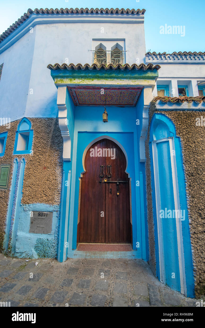 Typique, vieux, brown, finement sculptés, porte cloutée riad marocain et porte cadre et maison ancienne. bleu ville dans la médina de Chefchaouen, Maroc Banque D'Images