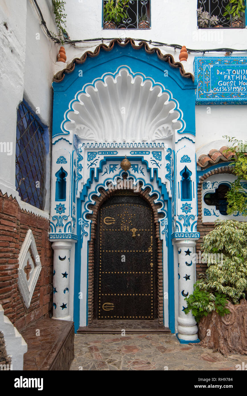 Typique, vieux, brown, finement sculptés, porte cloutée riad marocain et porte cadre et maison ancienne. bleu ville dans la médina de Chefchaouen, Maroc Banque D'Images