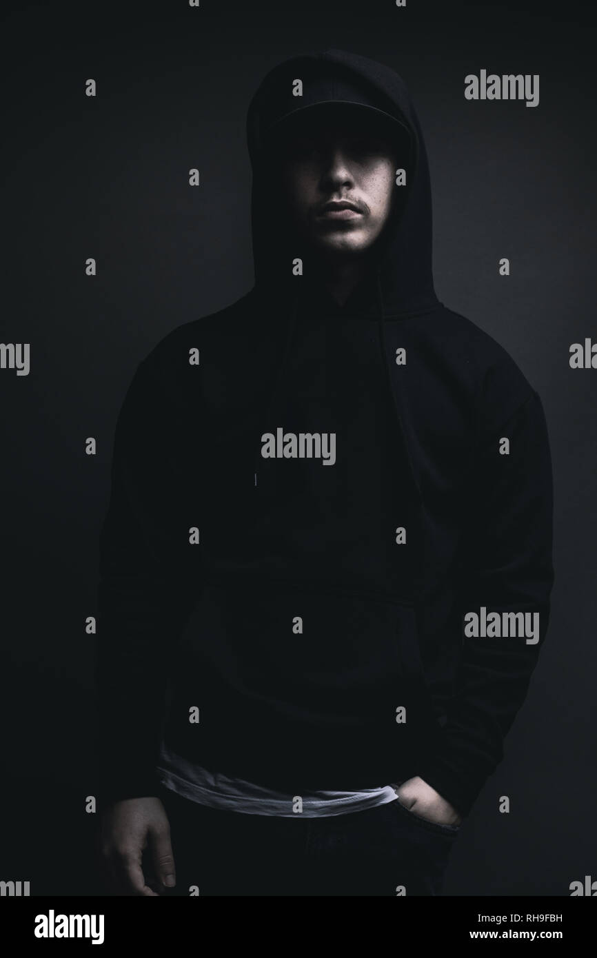 Jeune rappeur cool avec capuche noire et le chapeau, debout devant un fond  gris Photo Stock - Alamy