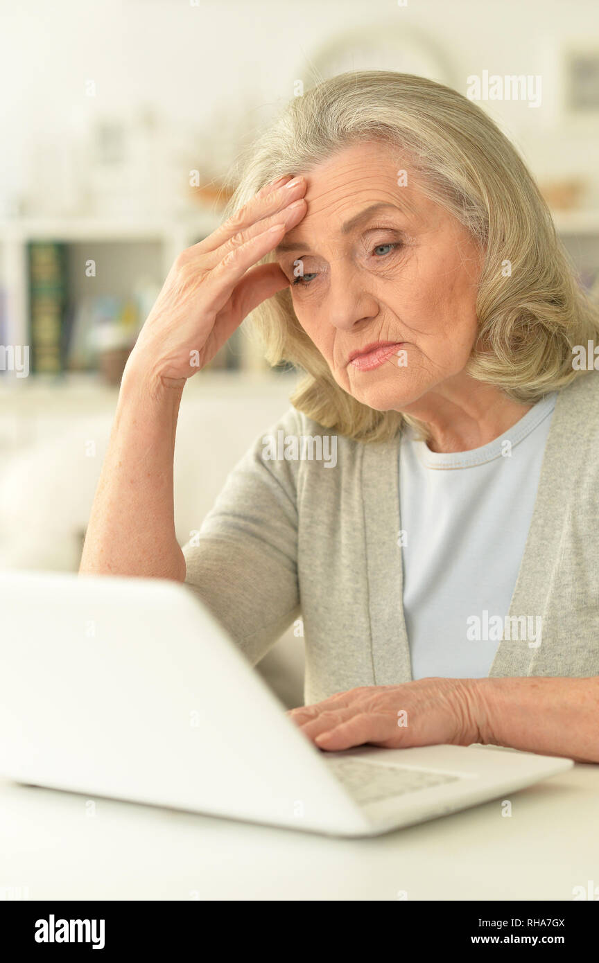Senior woman sitting at table with laptop Banque D'Images