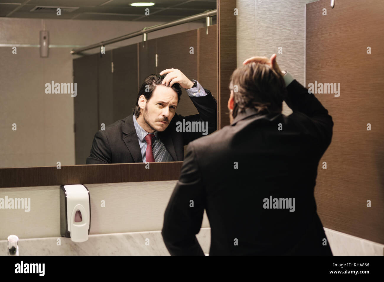 Inquiets Hispanic Business Man Looking At délié dans les toilettes du bureau Banque D'Images