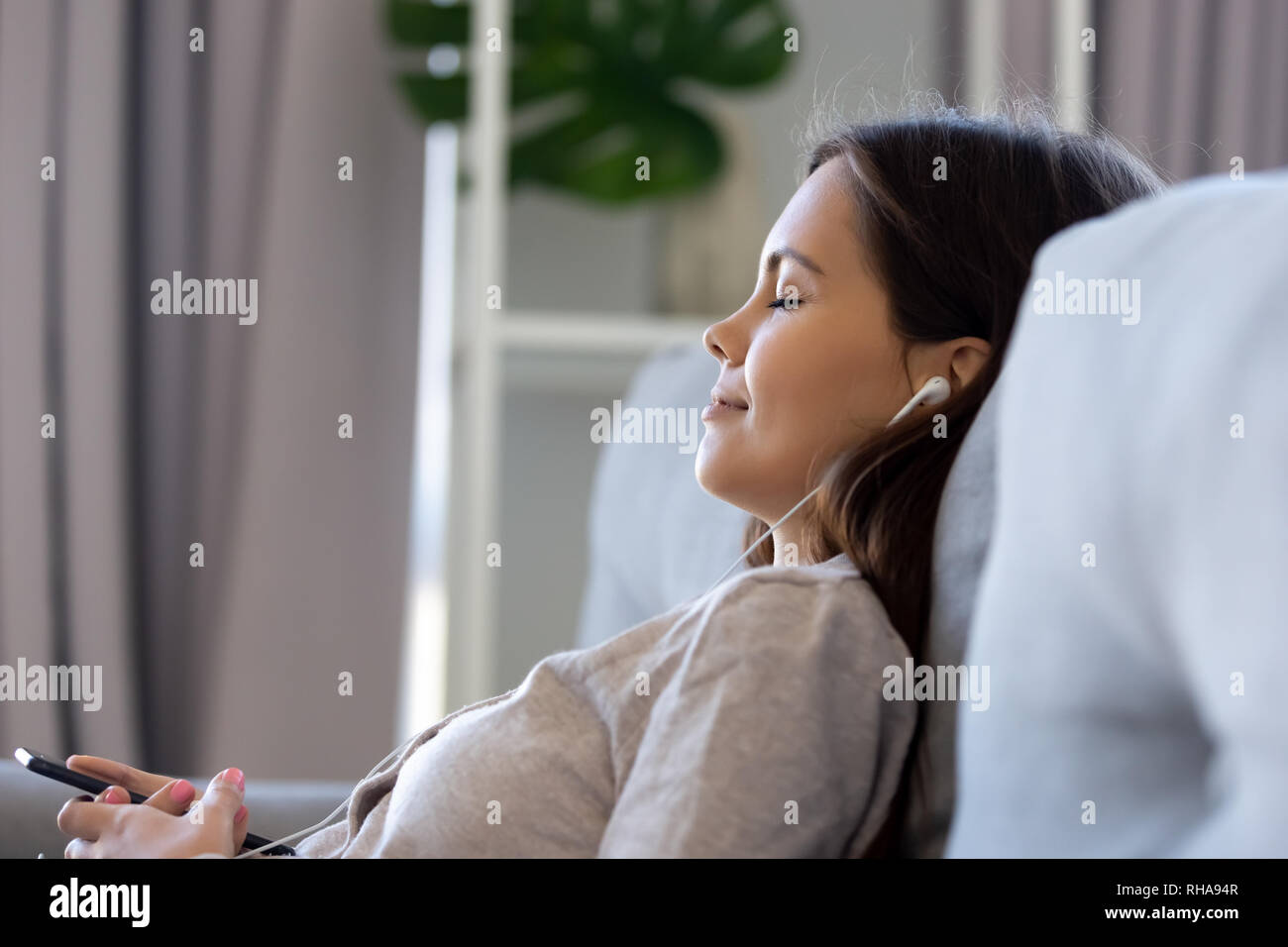 Young woman wearing earphones listening music sur smartphone app player Banque D'Images