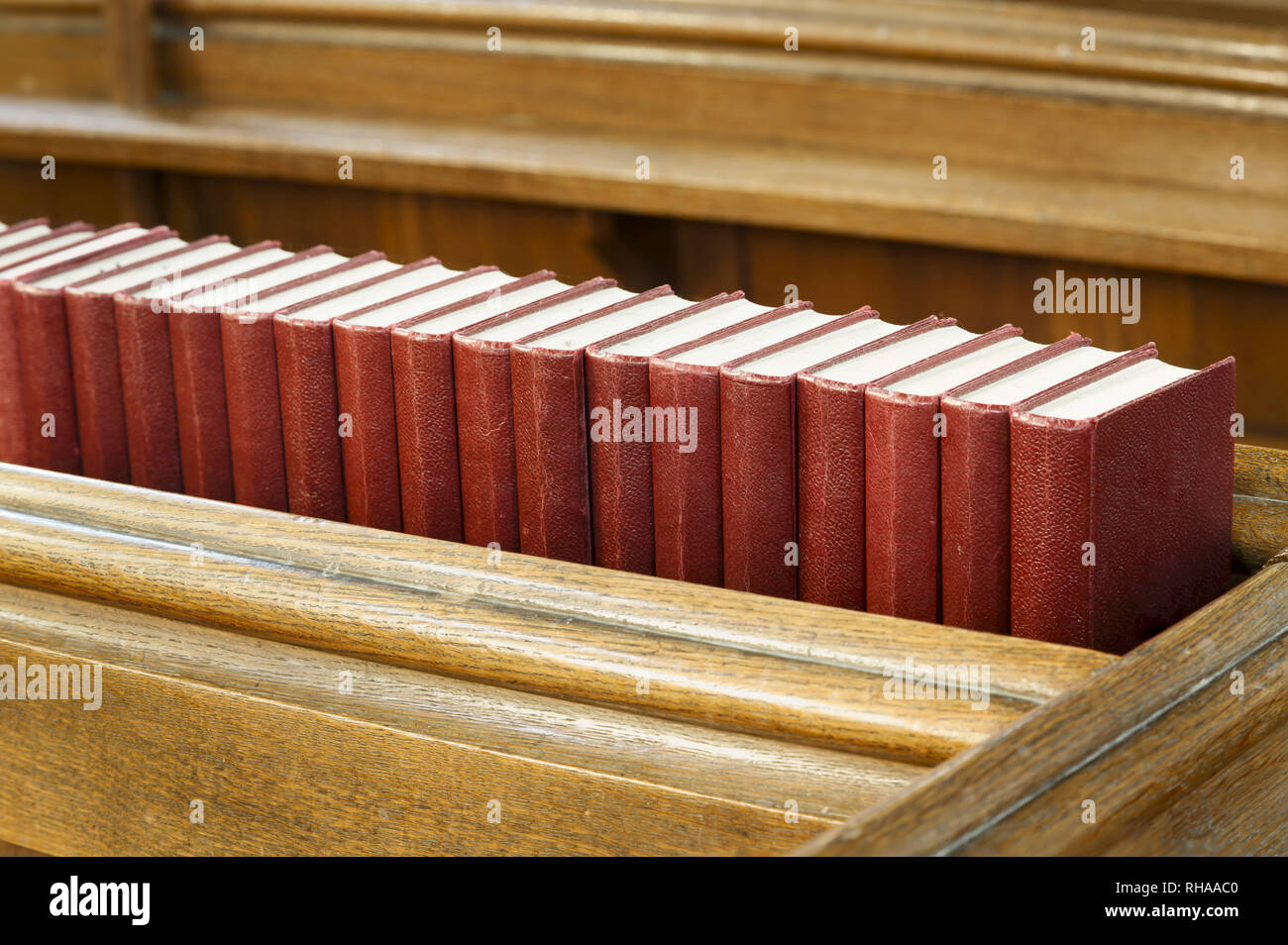 Libre d'une rangée de livres sur l'hymne rouge une ancienne église en bois pew. Représente la religion et la prière Banque D'Images