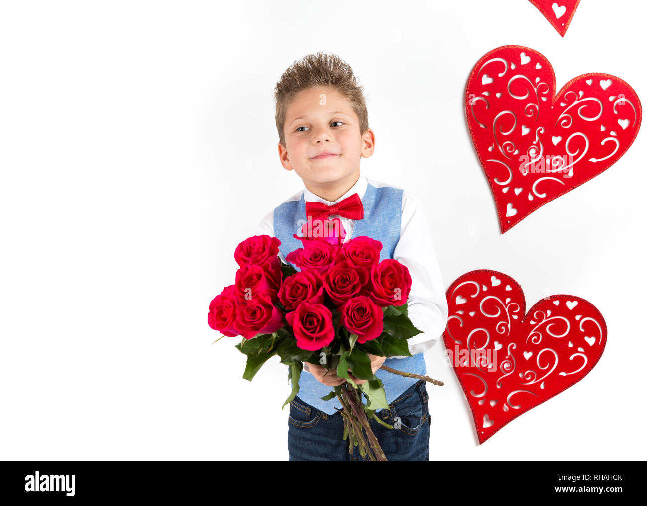 Garçon gentleman avec gilet bleu, rouge cravate papillon, roses rouges en forme de coeur et godet boîte-cadeau. Valentines Day kids. L'amour et l'amitié. 24 femme Banque D'Images