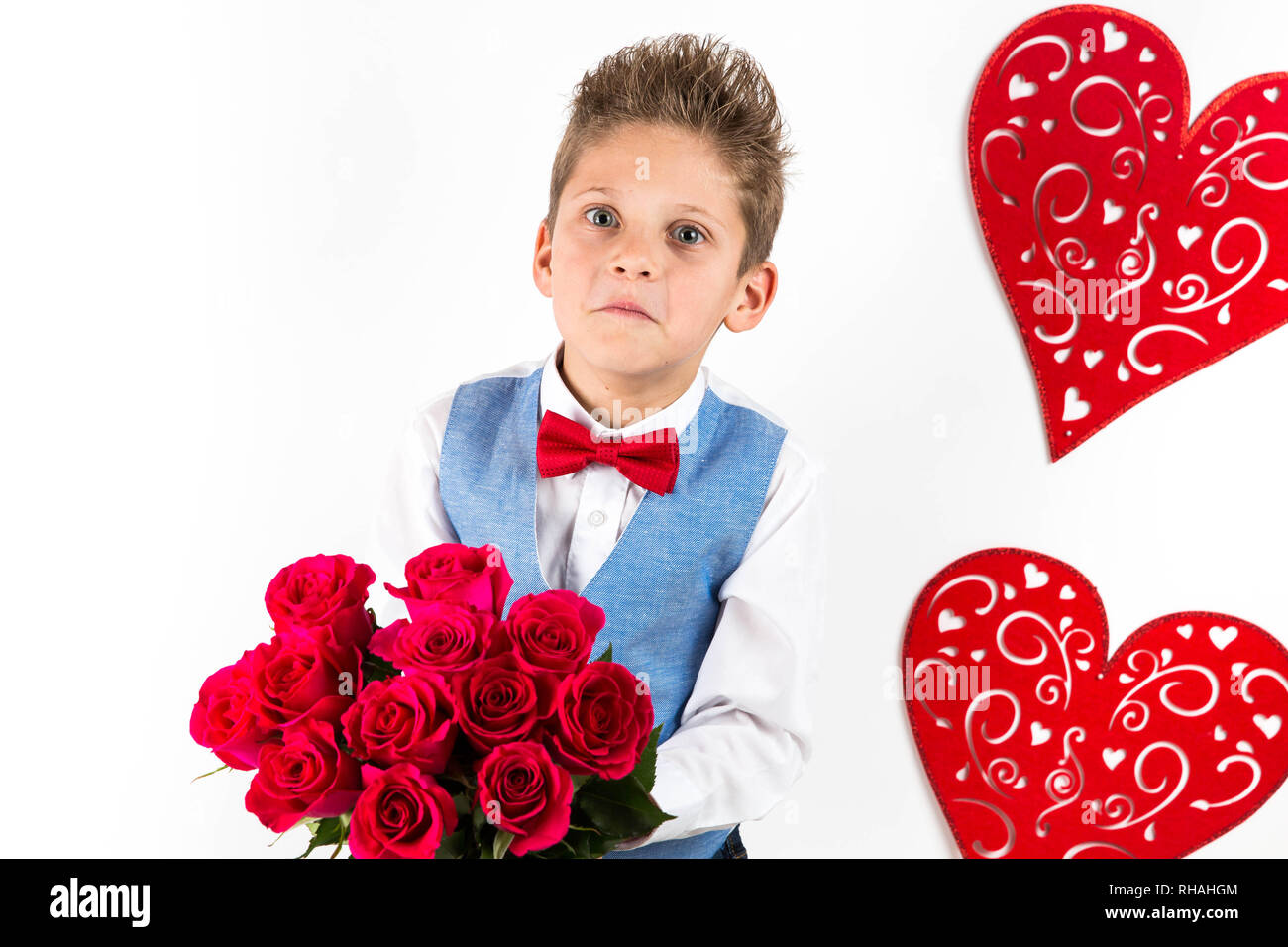 Garçon gentleman avec gilet bleu, rouge cravate papillon, roses rouges en forme de coeur et godet boîte-cadeau. Valentines Day kids. L'amour et l'amitié. 24 femme Banque D'Images