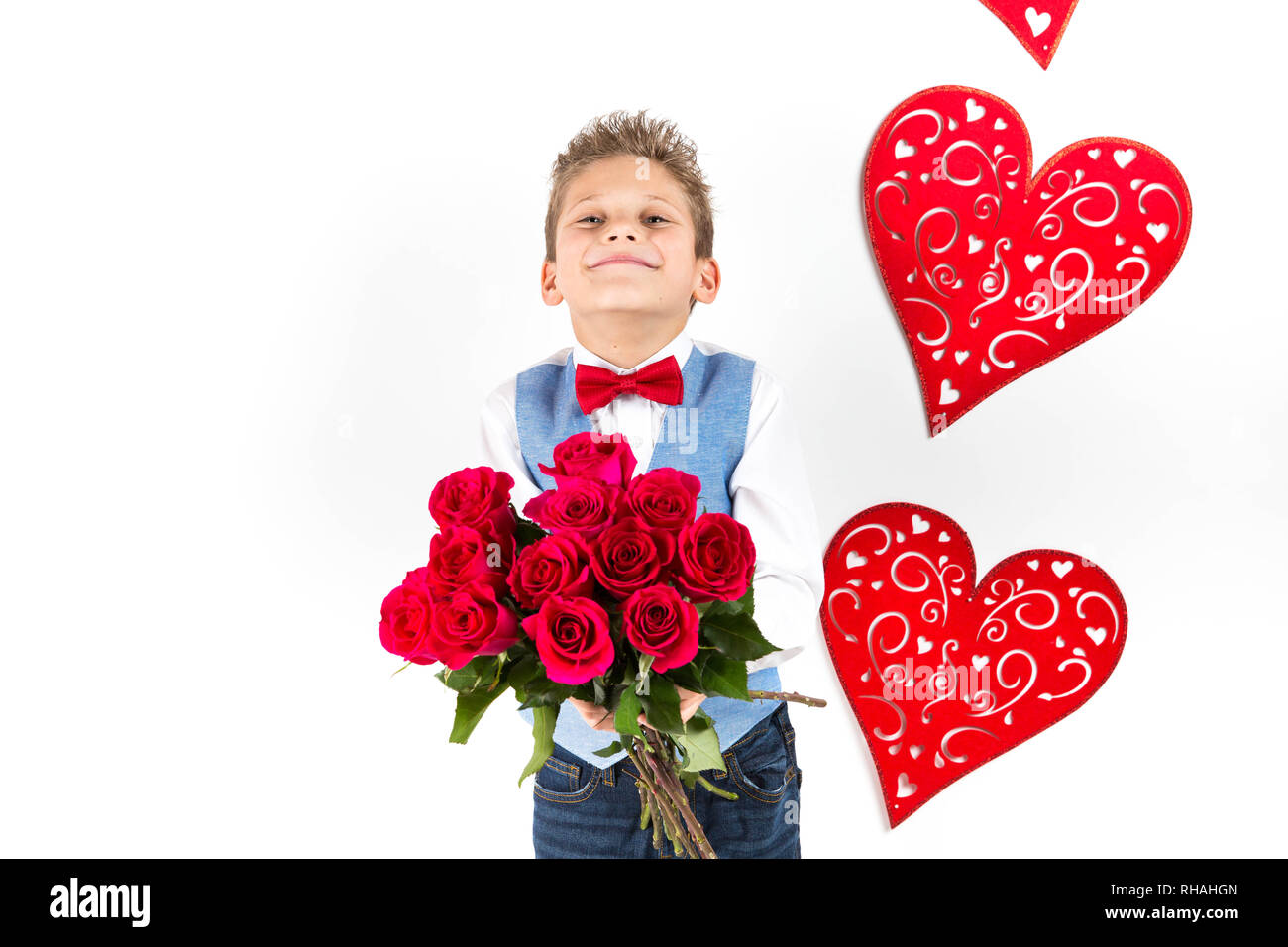 Garçon gentleman avec gilet bleu, rouge cravate papillon, roses rouges en forme de coeur et godet boîte-cadeau. Valentines Day kids. L'amour et l'amitié. 24 femme Banque D'Images