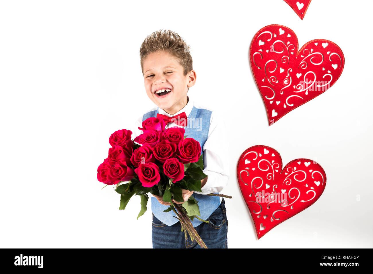 Garçon gentleman avec gilet bleu, rouge cravate papillon, roses rouges en forme de coeur et godet boîte-cadeau. Valentines Day kids. L'amour et l'amitié. 24 femme Banque D'Images