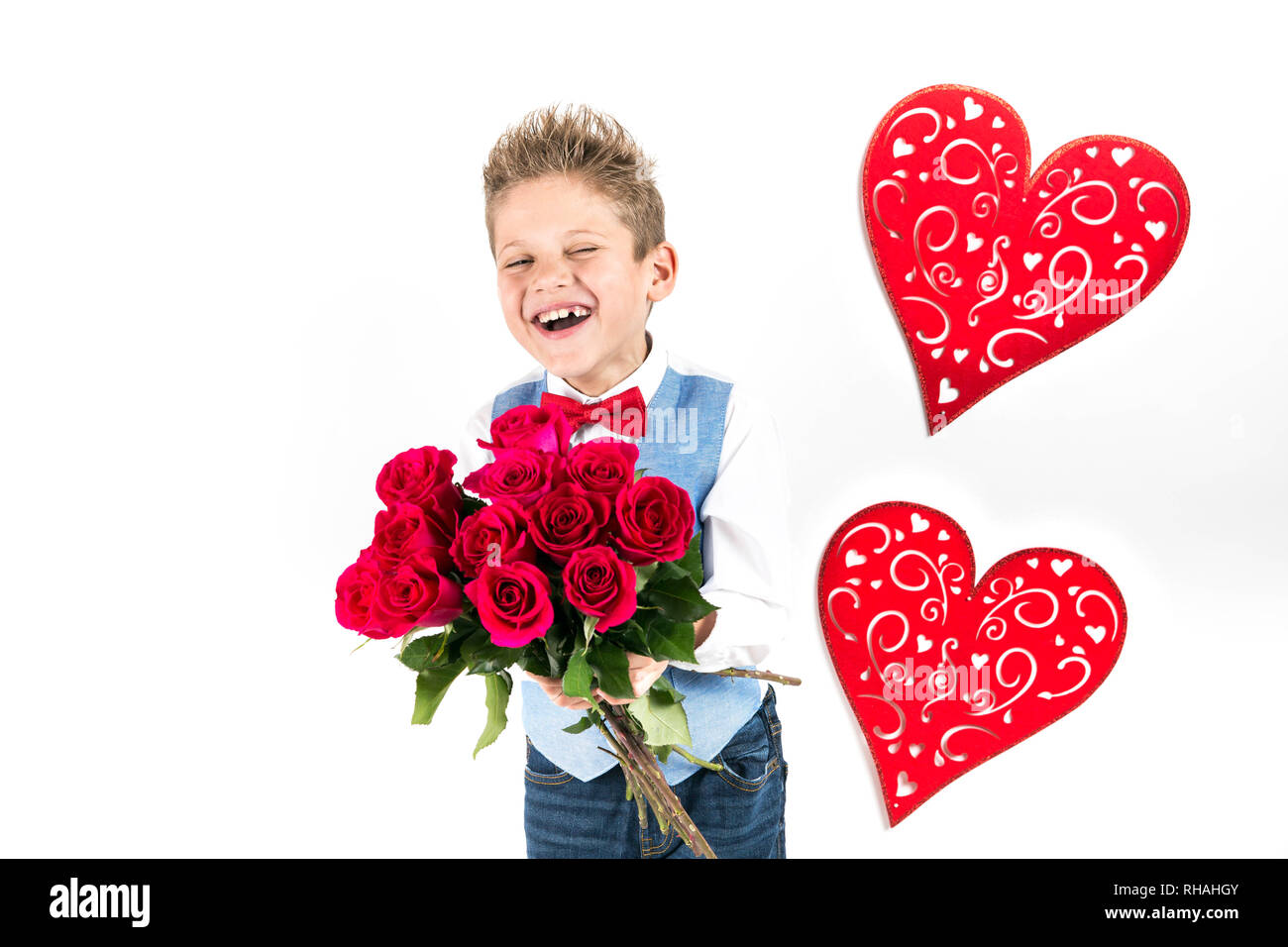 Garçon gentleman avec gilet bleu, rouge cravate papillon, roses rouges en forme de coeur et godet boîte-cadeau. Valentines Day kids. L'amour et l'amitié. 24 femme Banque D'Images