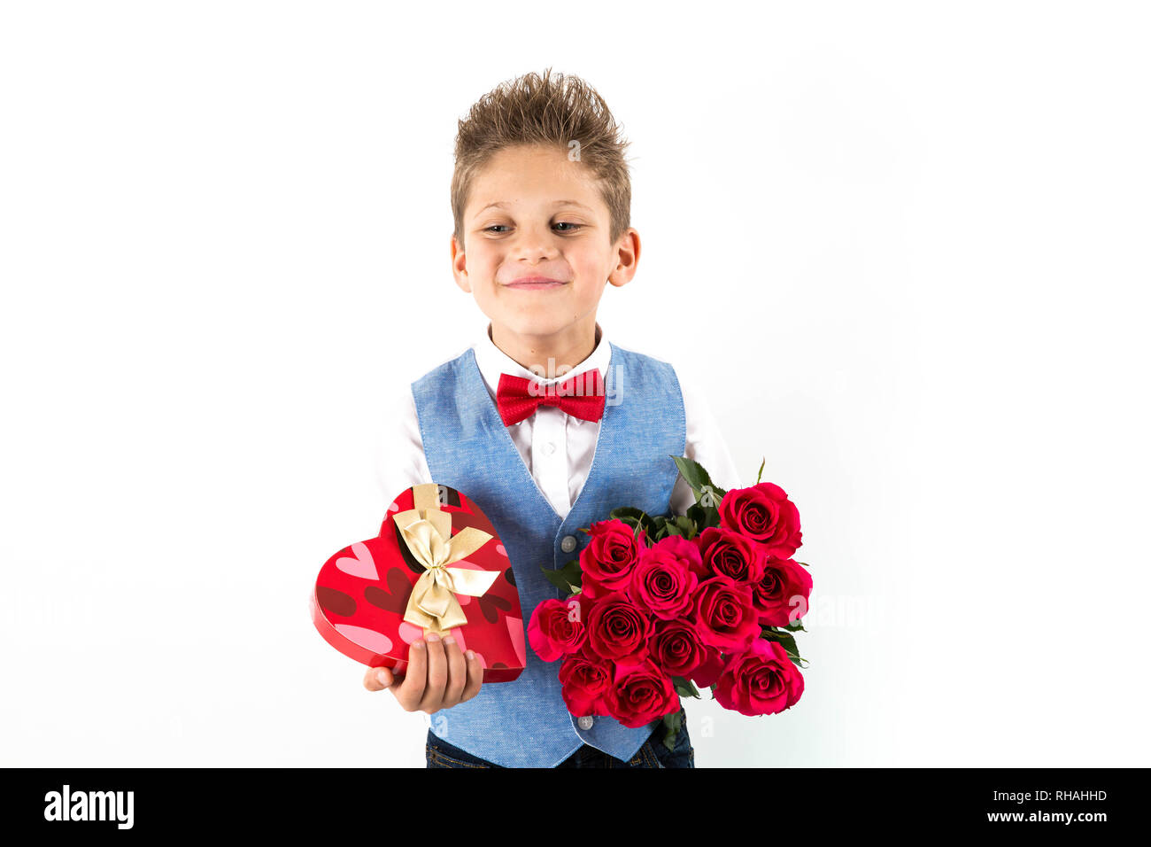 Garçon gentleman avec gilet bleu, rouge cravate papillon, roses rouges en forme de coeur et godet boîte-cadeau. Valentines Day kids. L'amour et l'amitié. 24 femme Banque D'Images