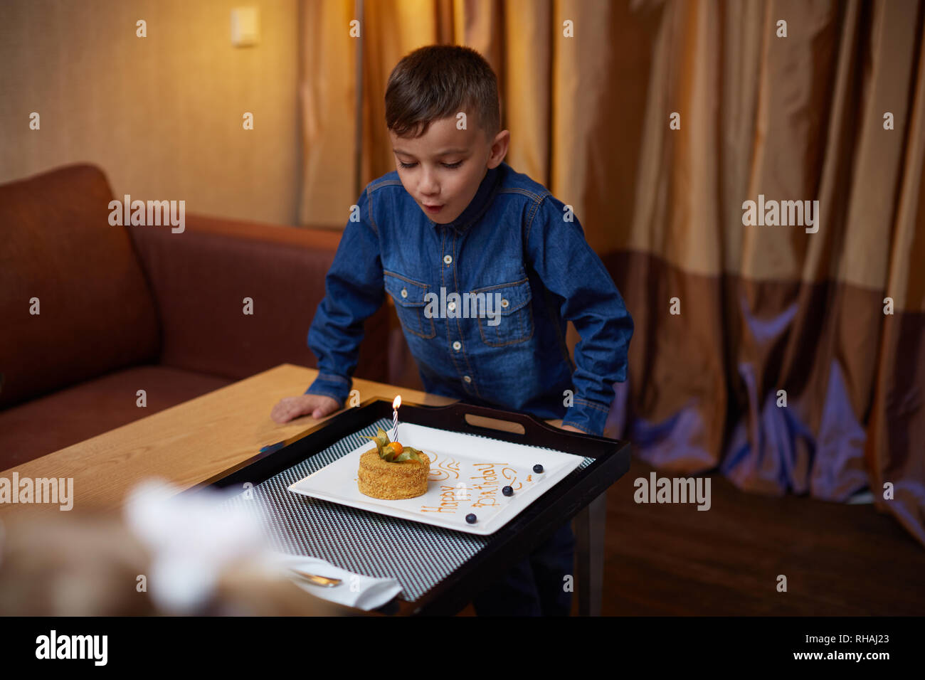 Anniversaire boy blowing candles sur le gâteau à la maison Banque D'Images