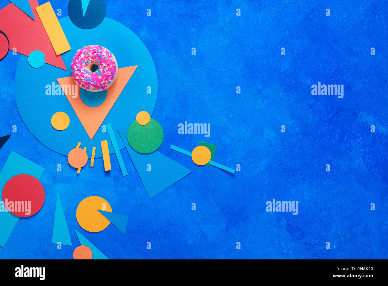 Beignet glacé rose sur un fond coloré avec des formes géométriques. Alimentation bloc couleur télévision coucha avec copie espace. Banque D'Images