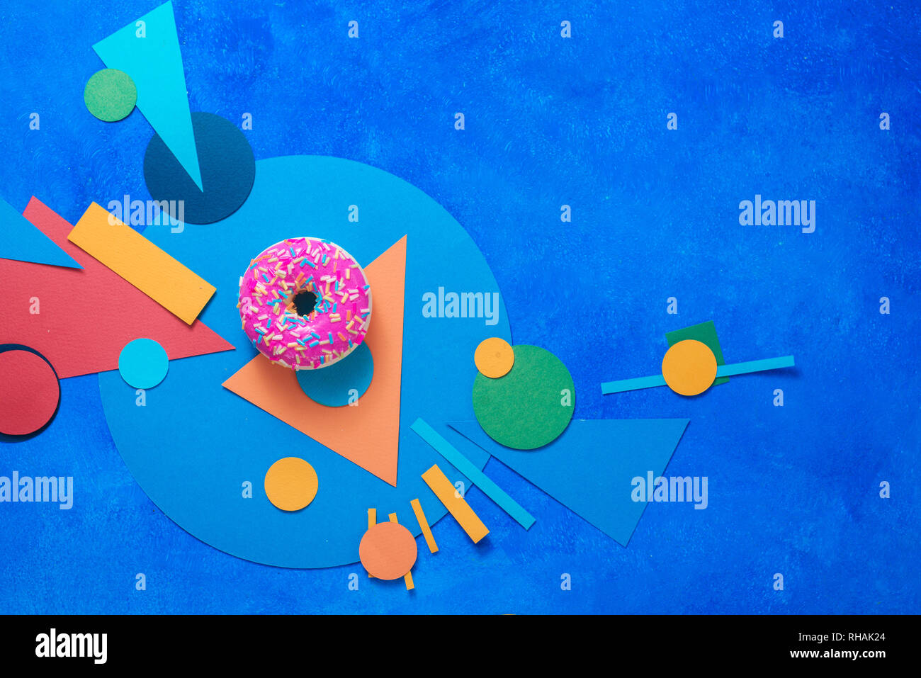 Beignet glacé rose sur un fond coloré avec des formes géométriques. Alimentation bloc couleur télévision coucha avec copie espace. Banque D'Images