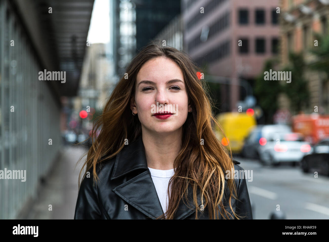 Belle jeune femme portant un trench-coat noir regardant la caméra. Jusqu'à la taille. Banque D'Images