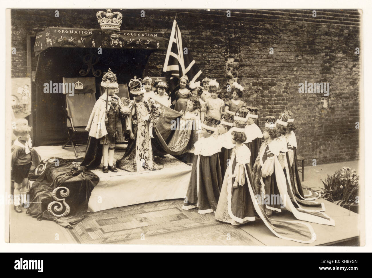 Carte postale originale de l'ère des années 1930 du couronnement du roi George VI et de la reine Elizabeth, des écoliers reprenant leur costume, date de 1937 au-dessus de l'étape, Royaume-Uni. Banque D'Images