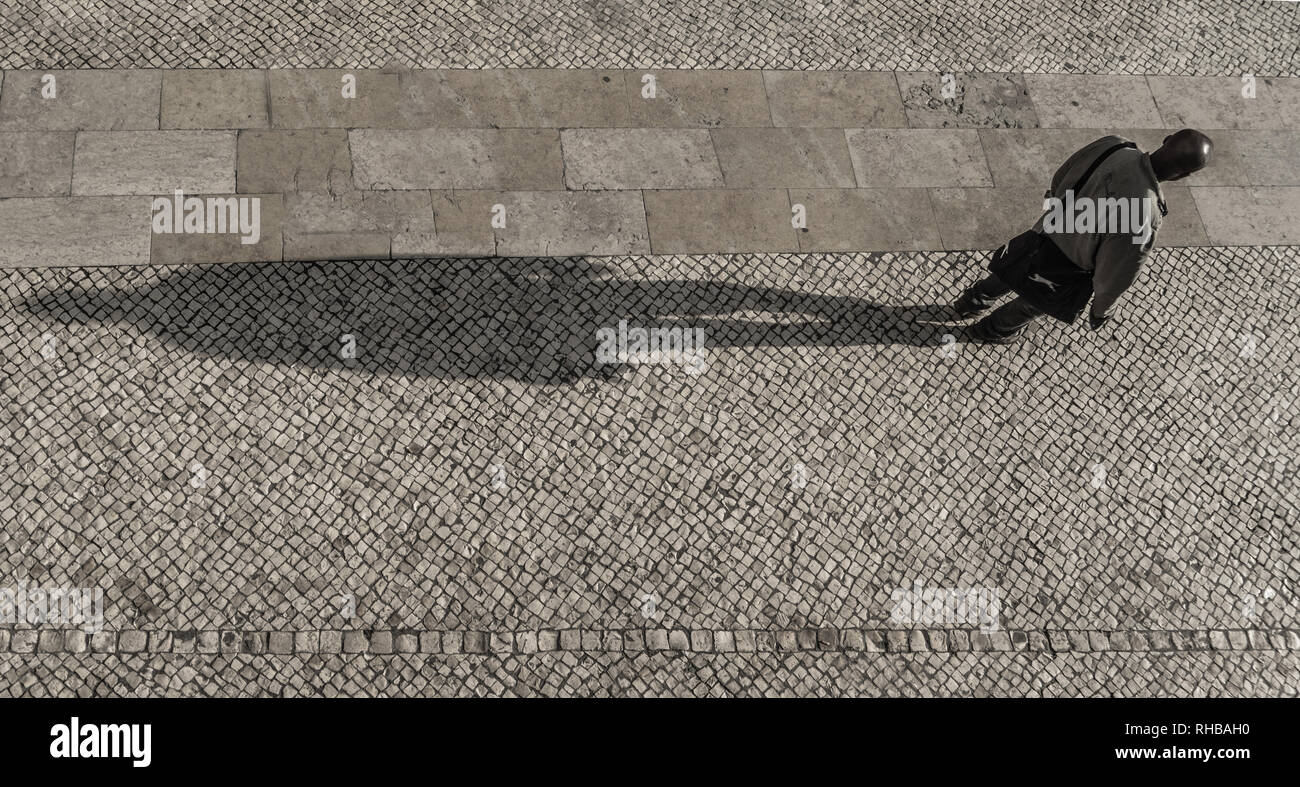 Lisbonne, quartier de Baixa, Un homme projetant une longue ombre dans l'après-midi. Banque D'Images