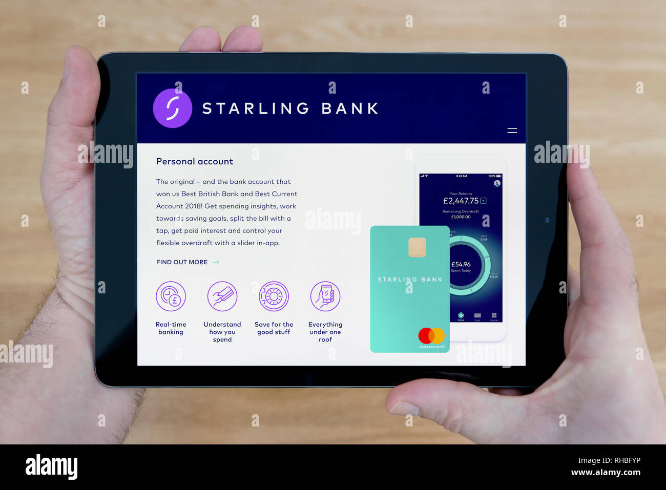 Un homme regarde le site web de banque Starling sur son iPad tablet device, tourné contre une table en bois page contexte (usage éditorial uniquement). Banque D'Images