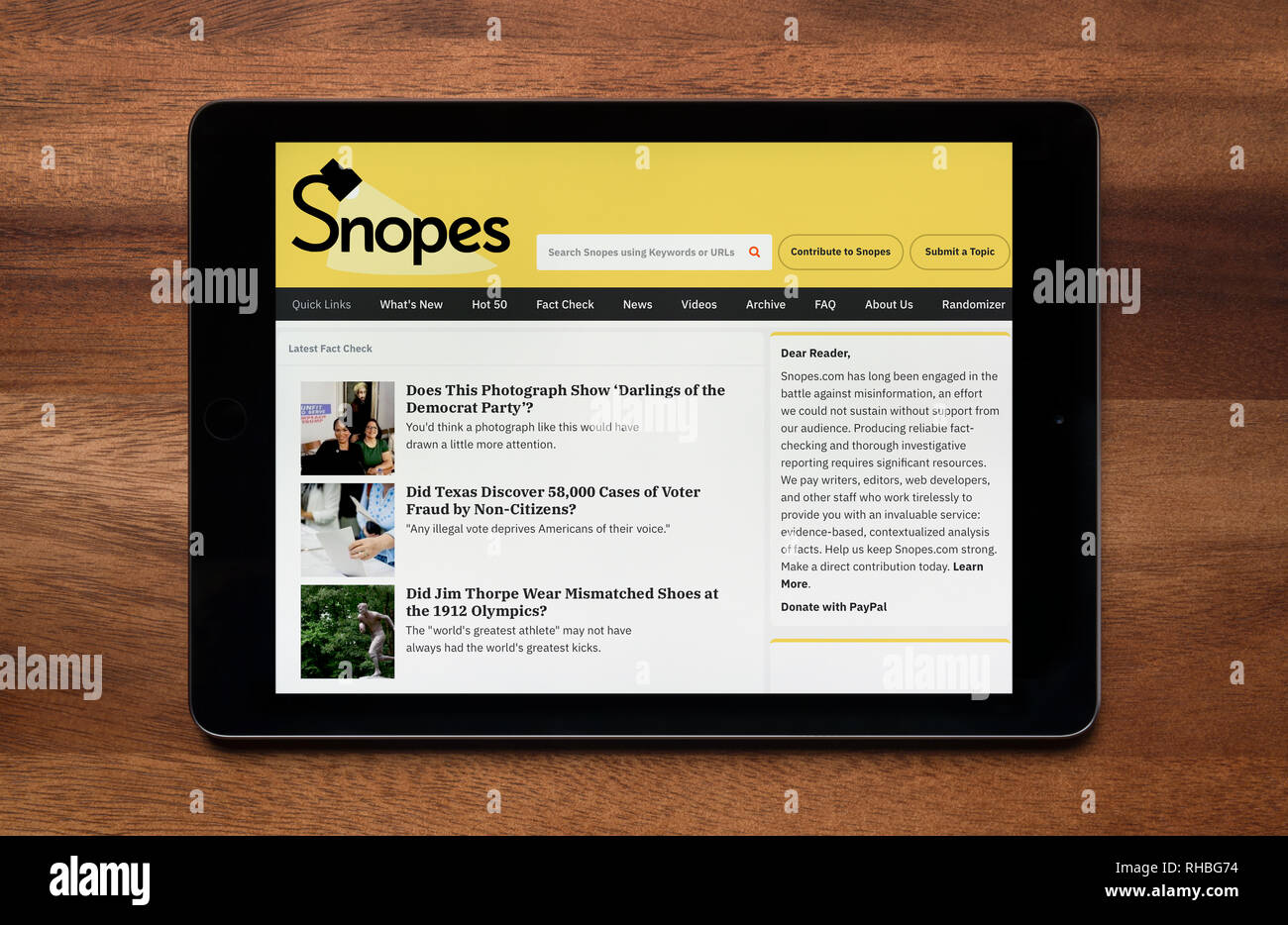Le site internet de Snopes est vu sur un iPad tablet, qui repose sur une table en bois (usage éditorial uniquement). Banque D'Images