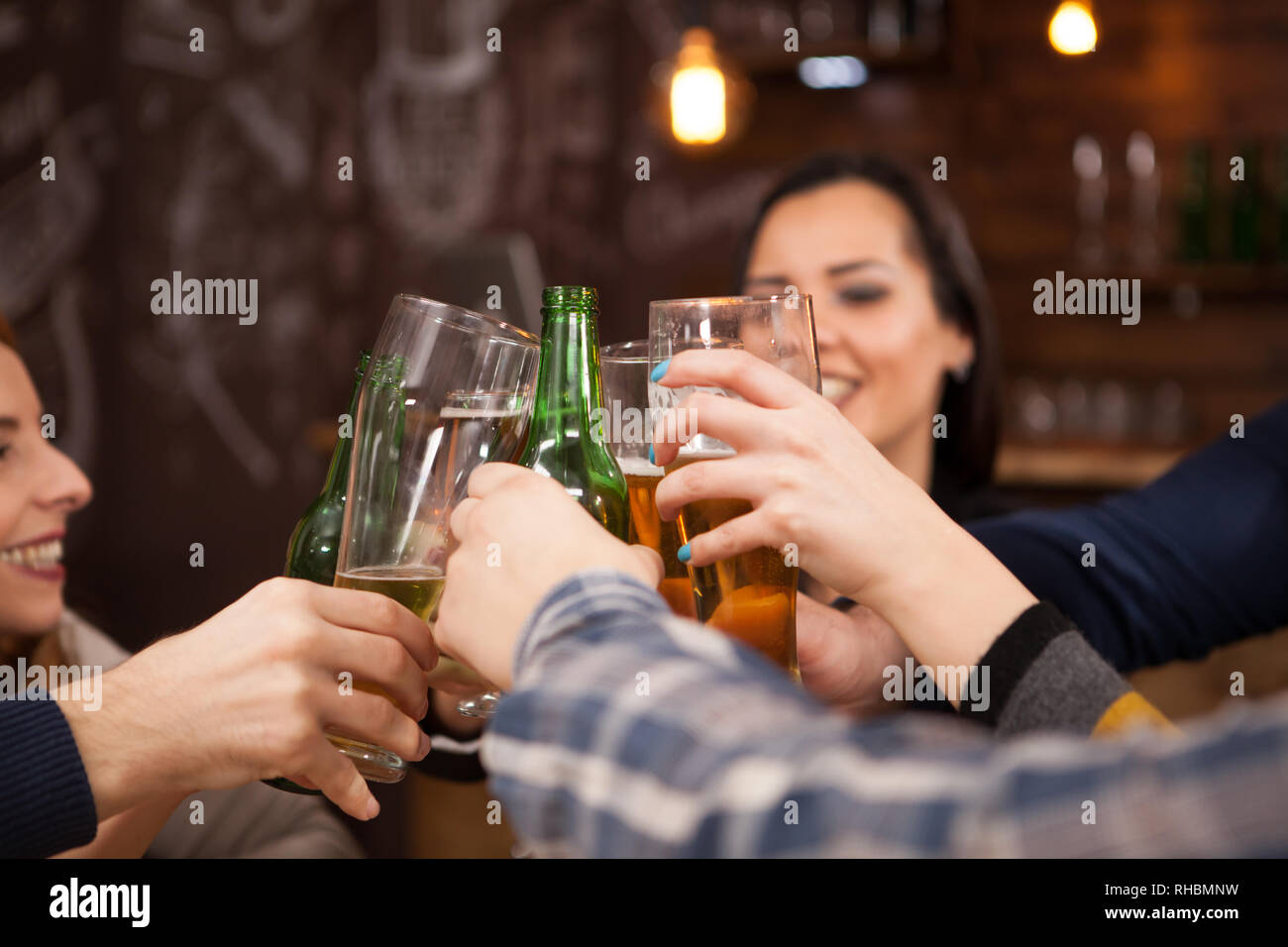 Happy friends clinking les bouteilles de bière. S'amusant dans un pub branché. Banque D'Images