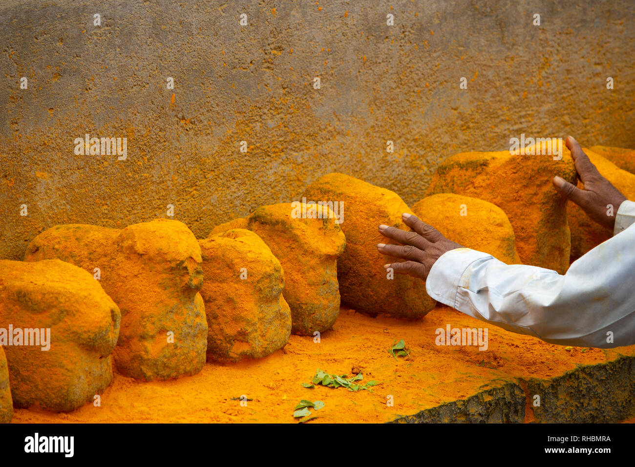 L'homme de toucher les pierres de couleur safran, Maharashtra, Inde Banque D'Images