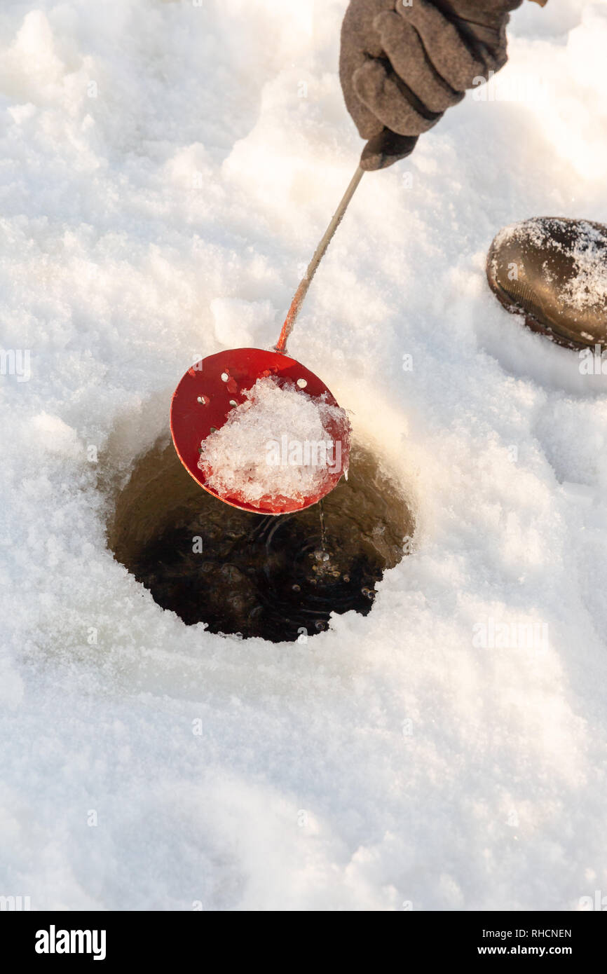 L'effacement du trou de pêche sur glace avec une glace faite maison une pelle. Banque D'Images
