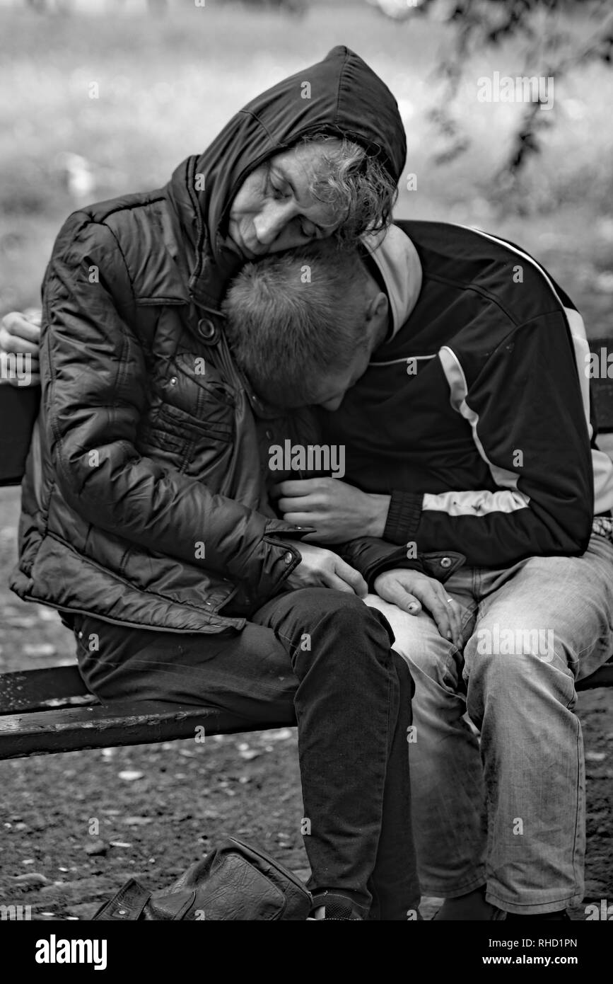 Un couple de sans-abri blottissez ensemble comme ils dorment sur un jour froid dans le Parc Planty, Cracovie, Pologne, Europe. Banque D'Images