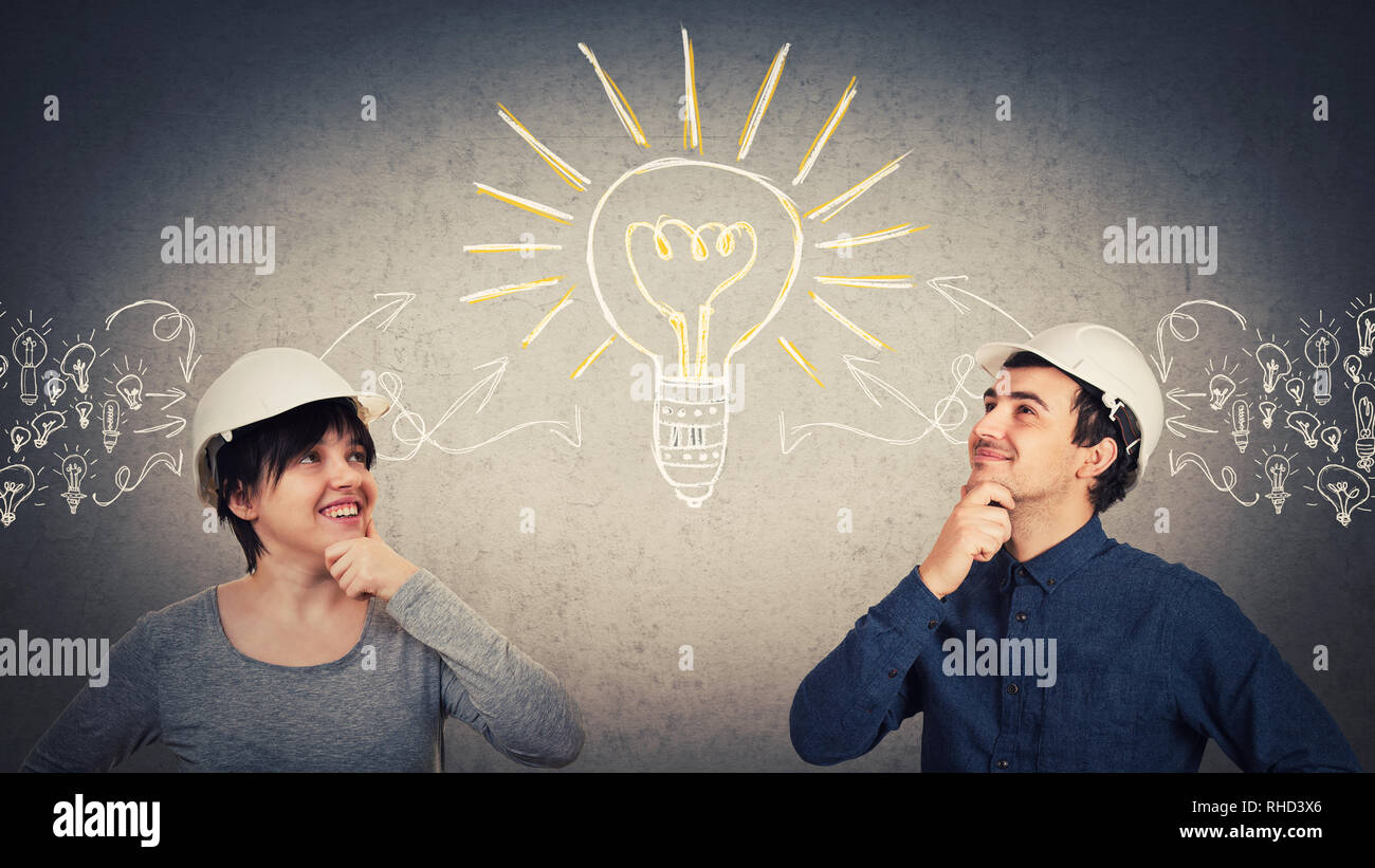 Les ingénieurs de construction ingénieux homme et femme portant casque de protection partager des réflexions ensemble rassembler les idées en une grosse ampoule électrique. L'échange objectif Banque D'Images