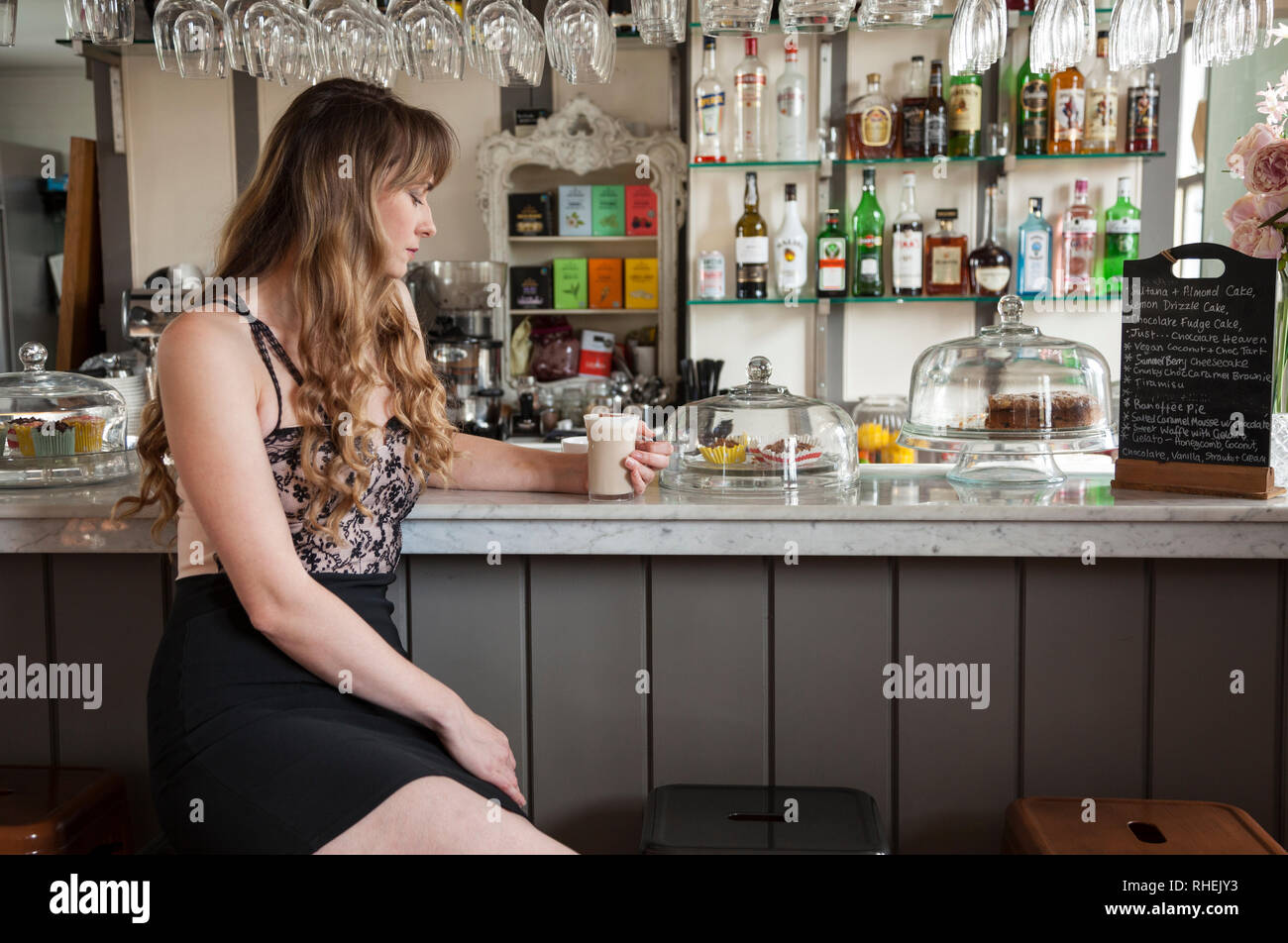 Dame en robe courte, seuls à la barre dans le Roydon Mill, Restaurant, Essex Banque D'Images