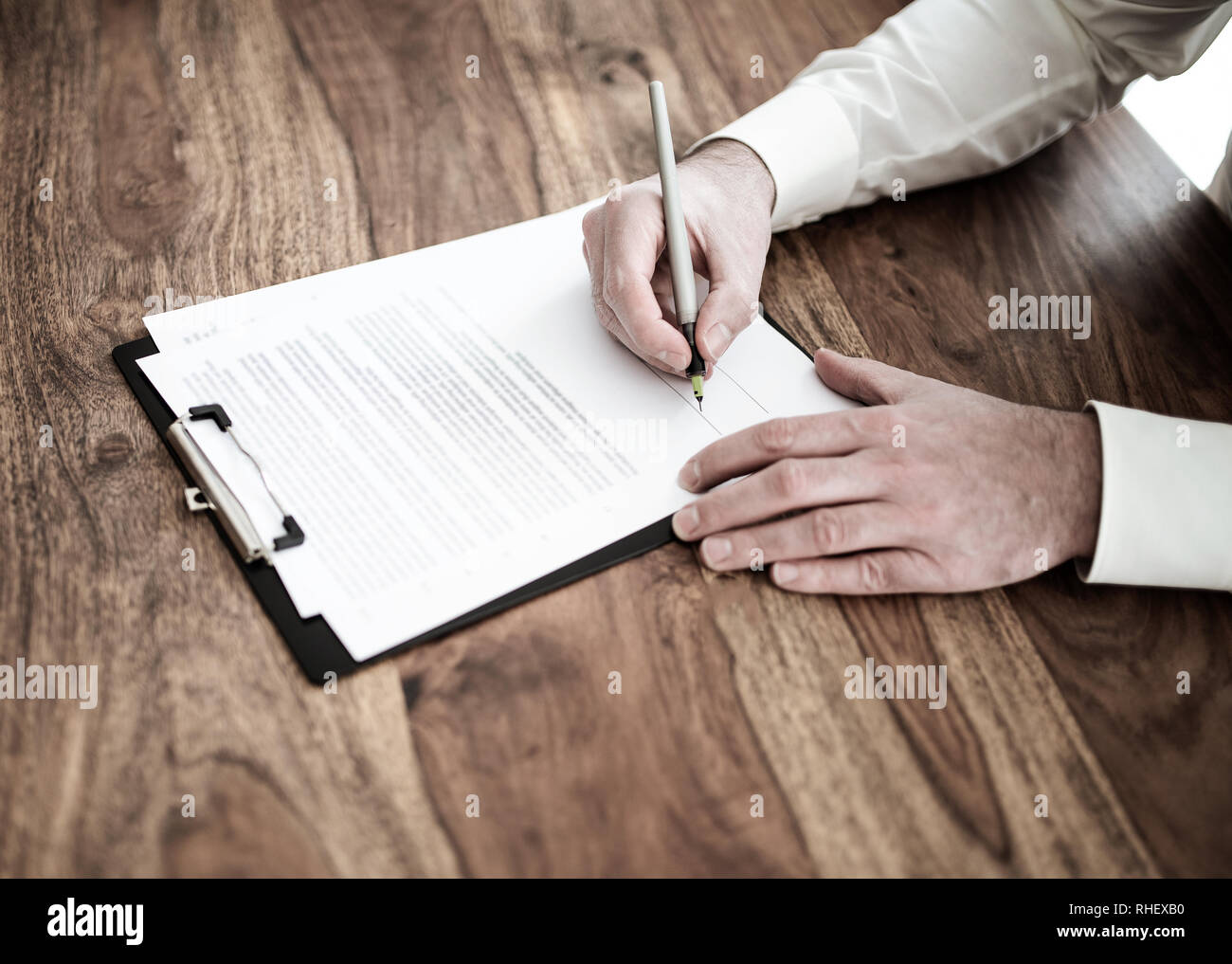 Homme signature contrat ou document au bureau en bois Banque D'Images