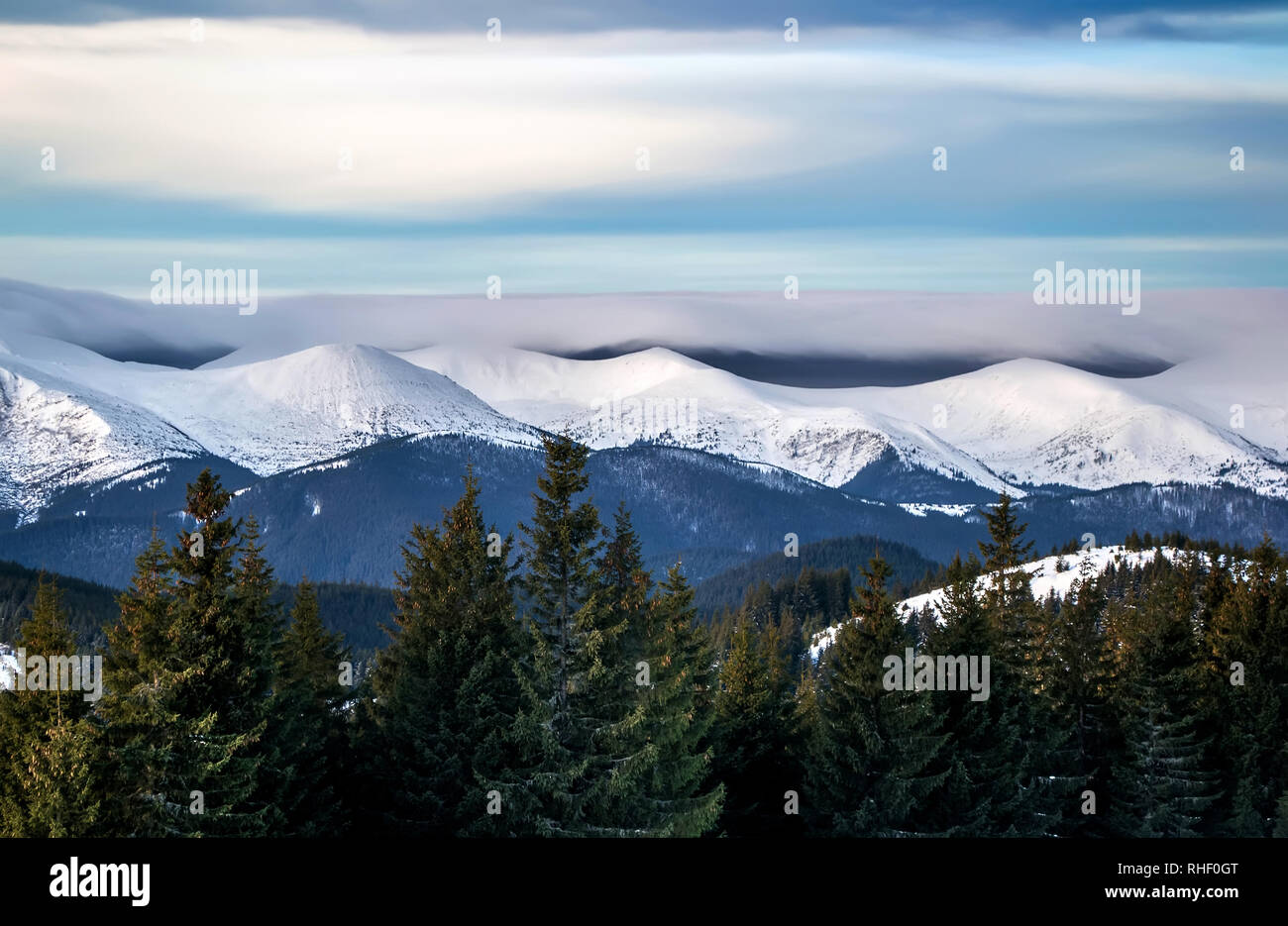 Paysage d'hiver d'une montagne enneigée plage sous de gros nuages sombres. Skyline spectaculaire. Les arbres en premier plan vert Banque D'Images