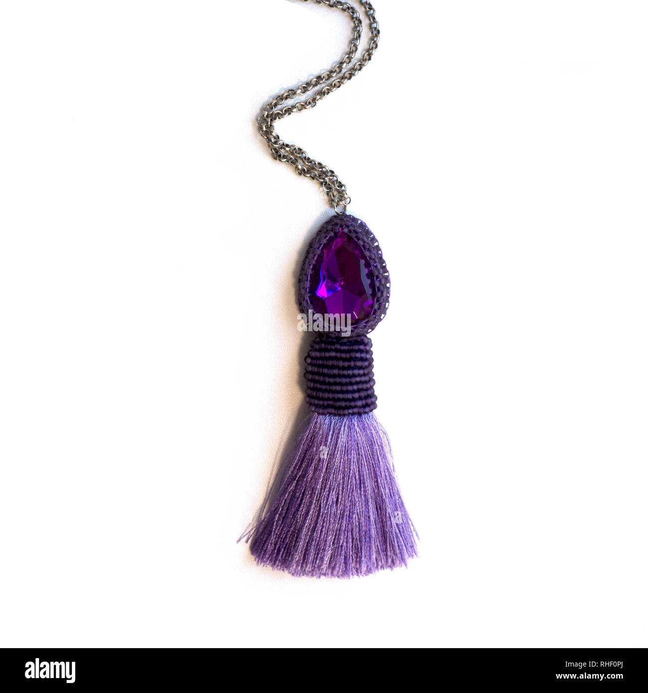 Le pendentif fait à la main sur une chaîne et d'un strass violet et un pinceau de soie. Banque D'Images