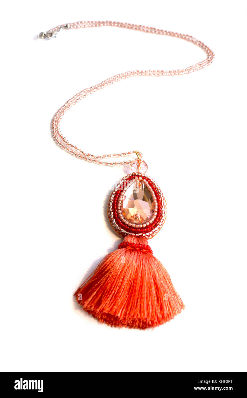 Le pendentif fait à la main sur une chaîne et un strass orange et un pinceau de soie. Banque D'Images